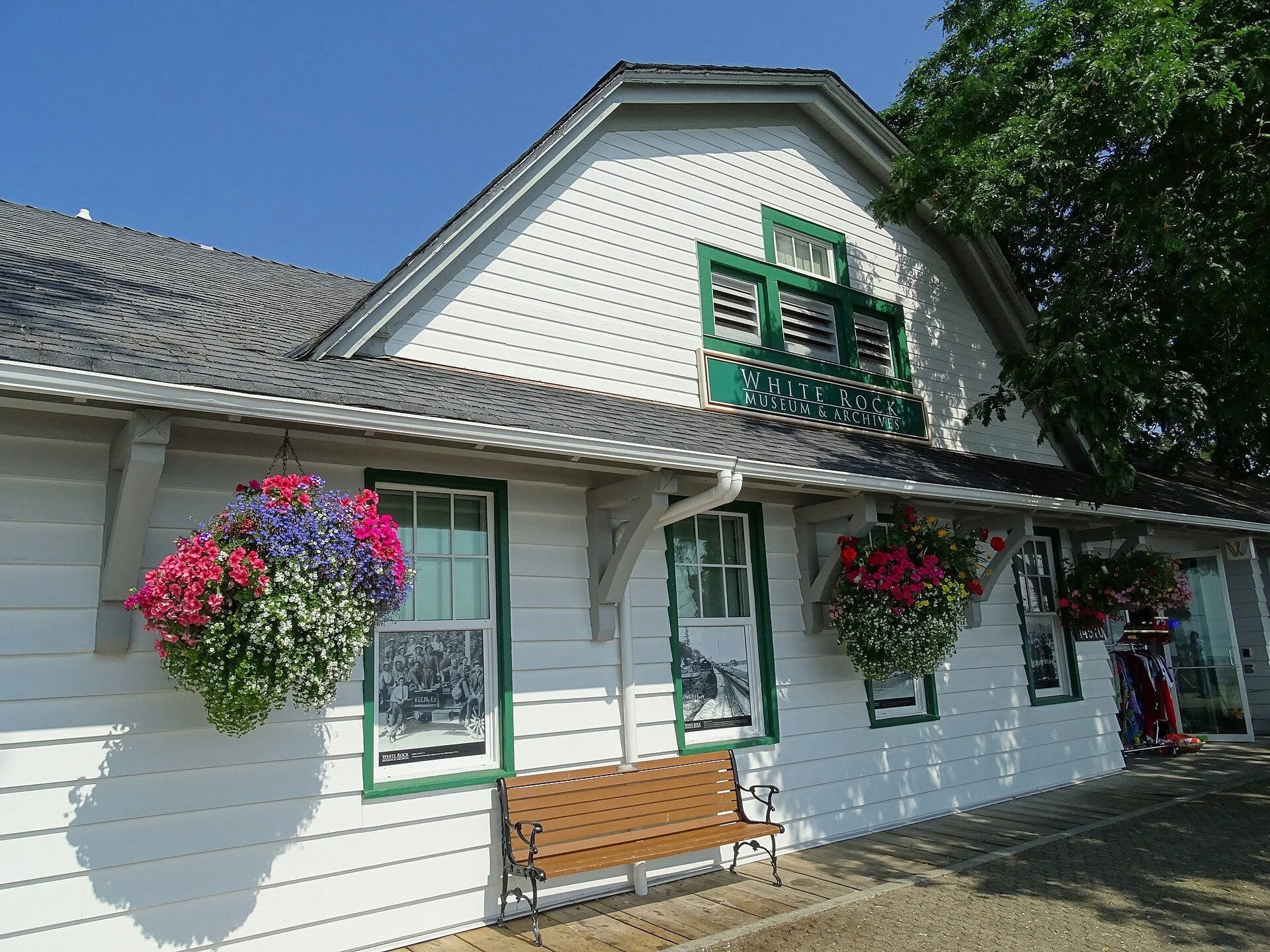 The white heritage building of the White Rock Museum and Archives with hanging flower baskets.