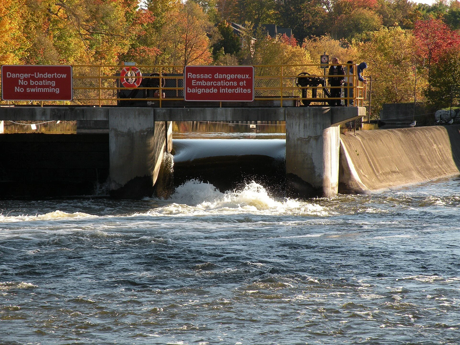 Water rushing through the dam at the Lindsay lock on the Scugog River, framed by autumn trees.