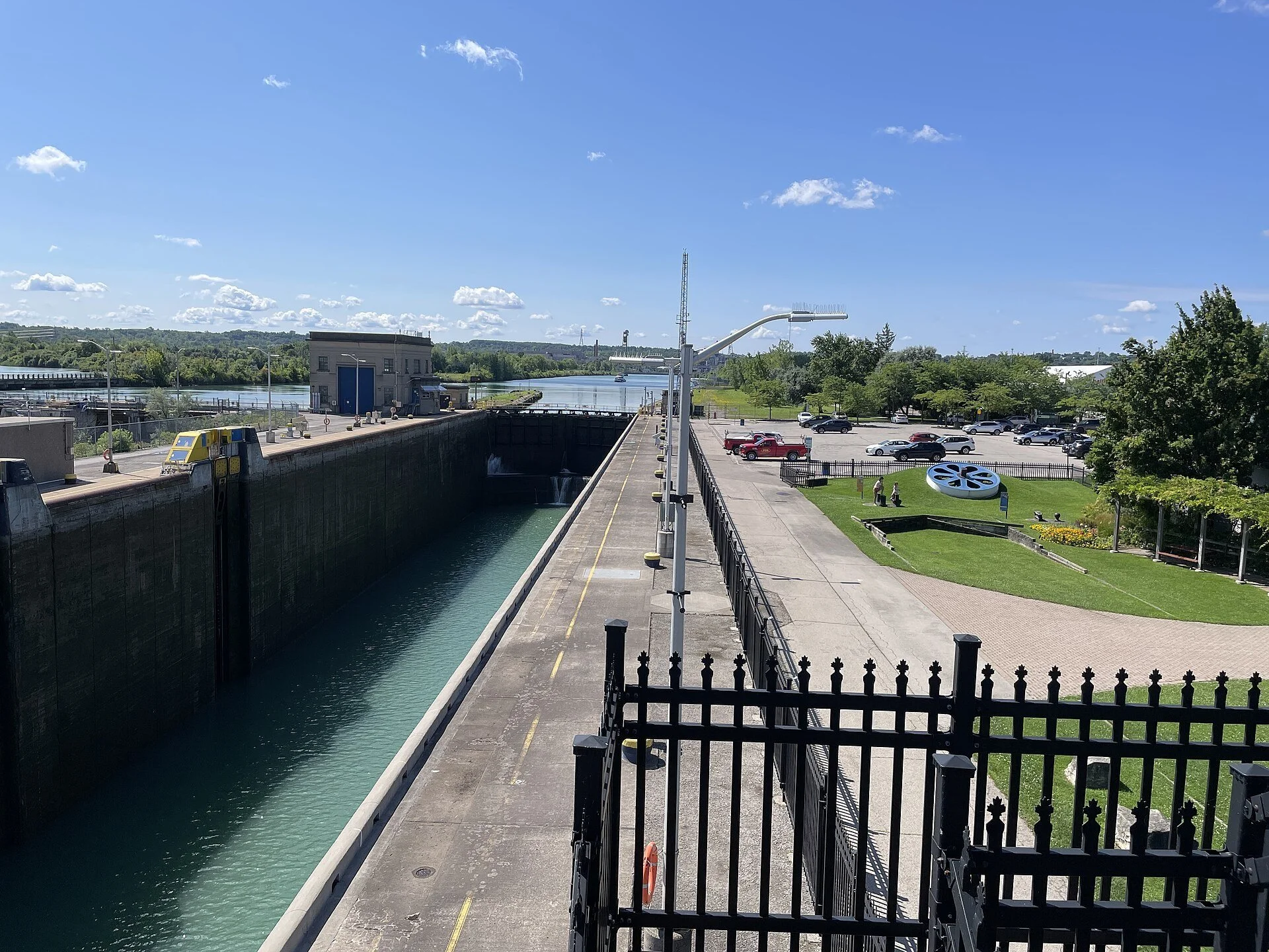 Welland Canal Lock 3 seen from the observation deck in St. Catharines on a sunny day, with the lock wall and a fenced walkway.