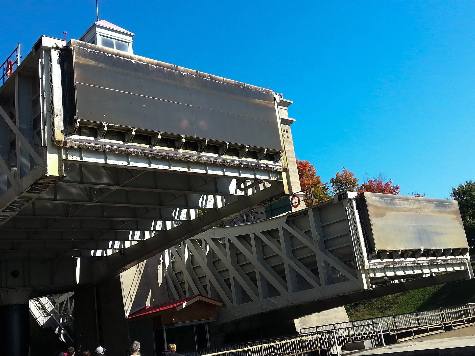 One of the giant water-filled tubs of the Peterborough Lift Lock raised high in mid-lift against a blue sky.