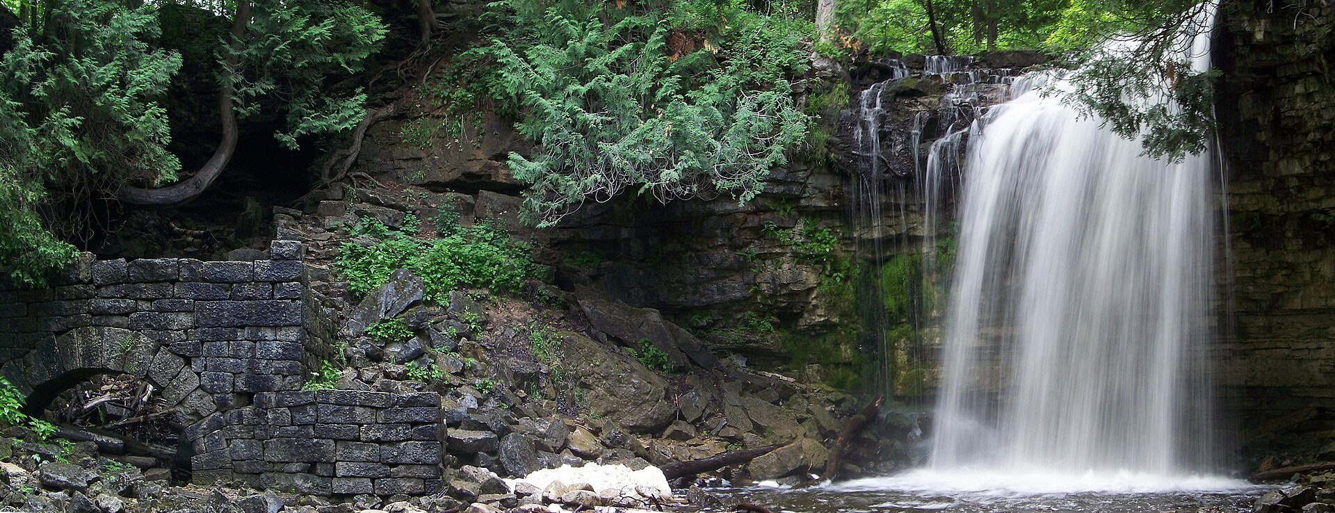 Hilton Falls pouring over a rock ledge beside the stone walls of an old mill ruin.