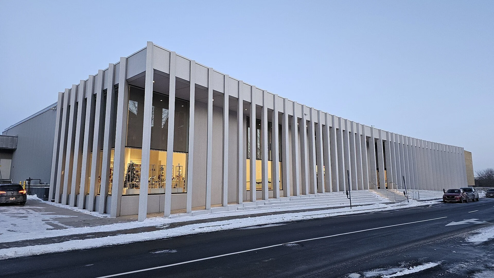 The white-columned modern facade of the Beaverbrook Art Gallery in Fredericton, New Brunswick, at dusk in winter.