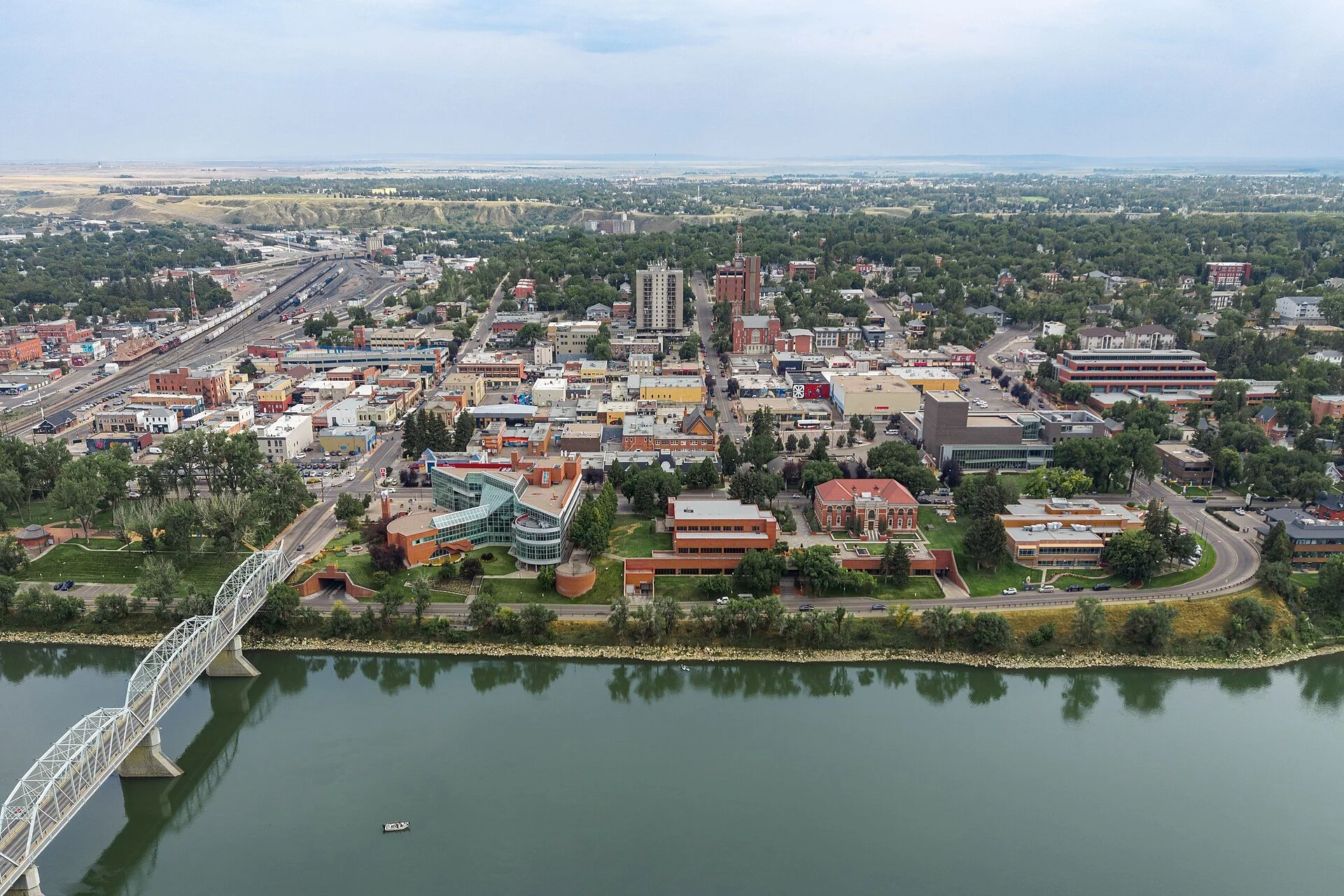 Aerial view of downtown Medicine Hat beside the South Saskatchewan River, with a bridge at the left.