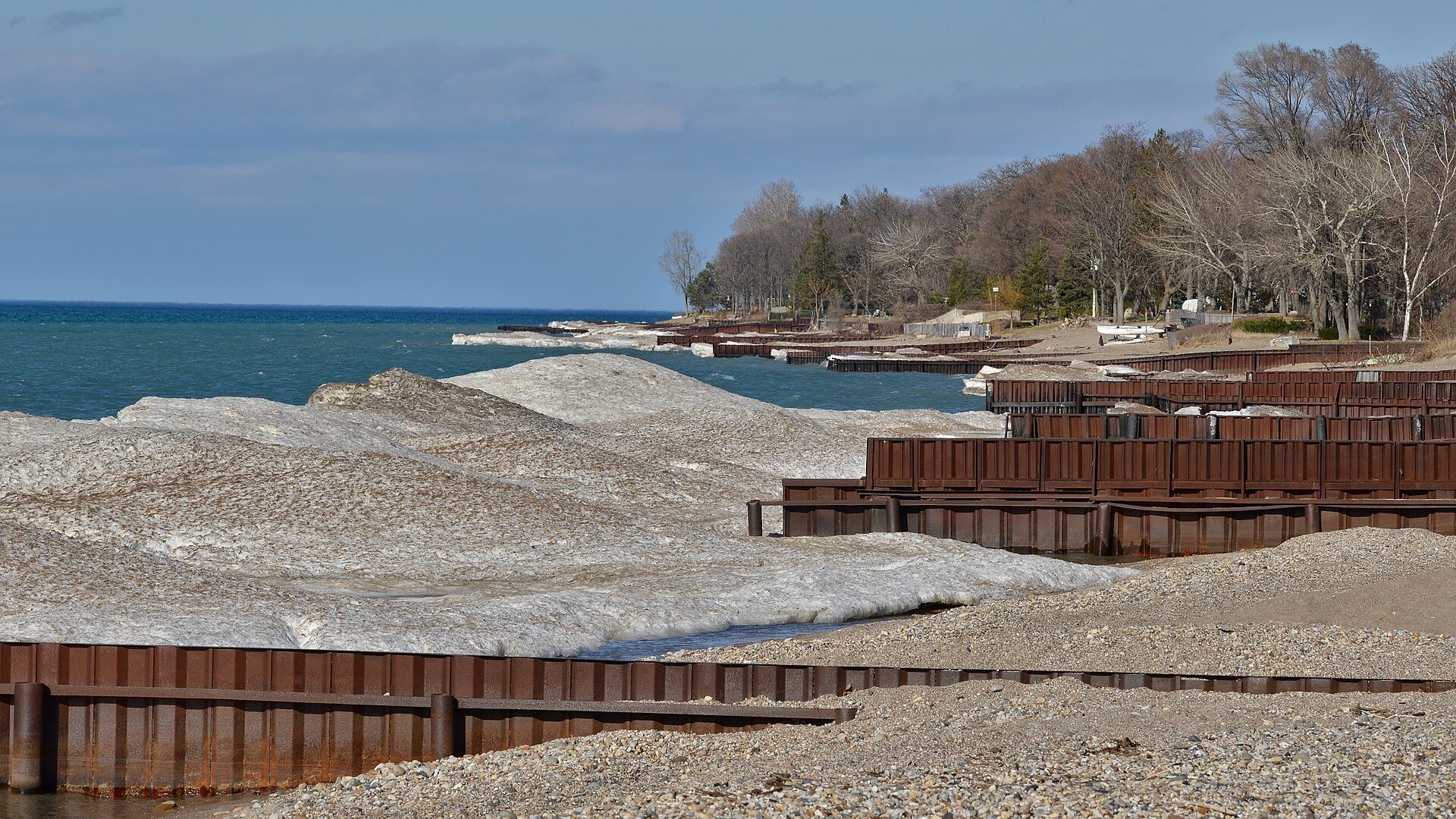 Leftover shore ice, steel breakwalls and a stony beach on the Lake Huron shoreline at Canatara Park in Sarnia, Ontario, in early spring.