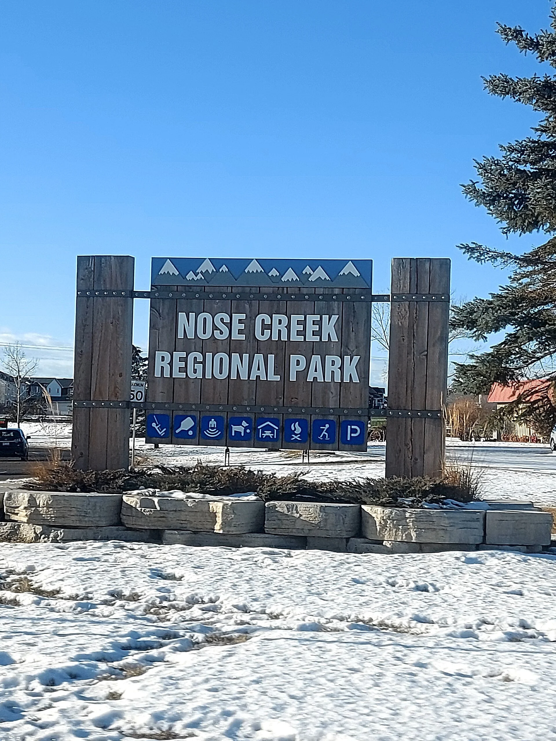 The Nose Creek Regional Park sign under fresh snow in Airdrie, Alberta.