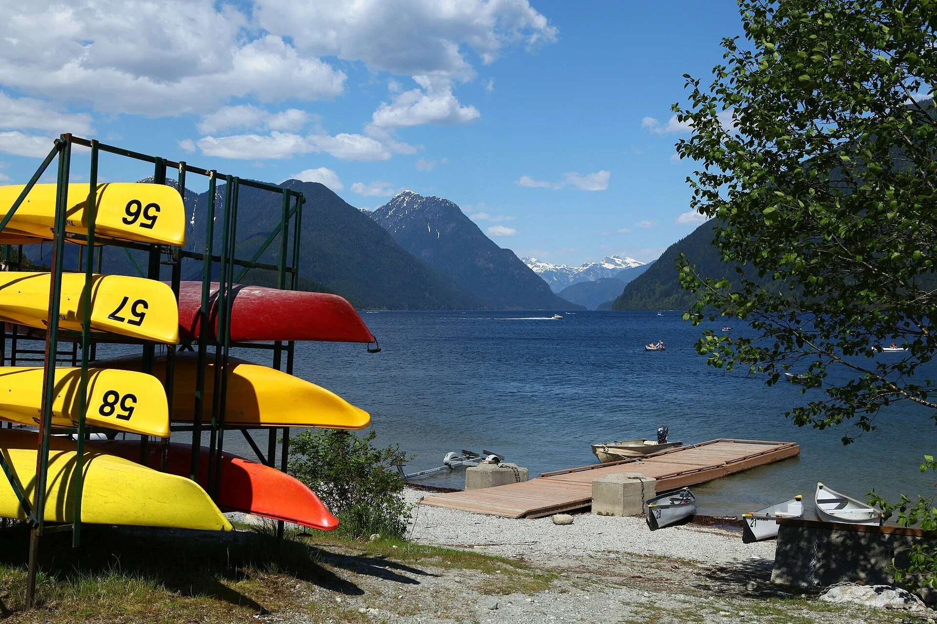 Yellow and red kayaks on a rack beside Alouette Lake in Golden Ears Provincial Park, with mountains across the water.