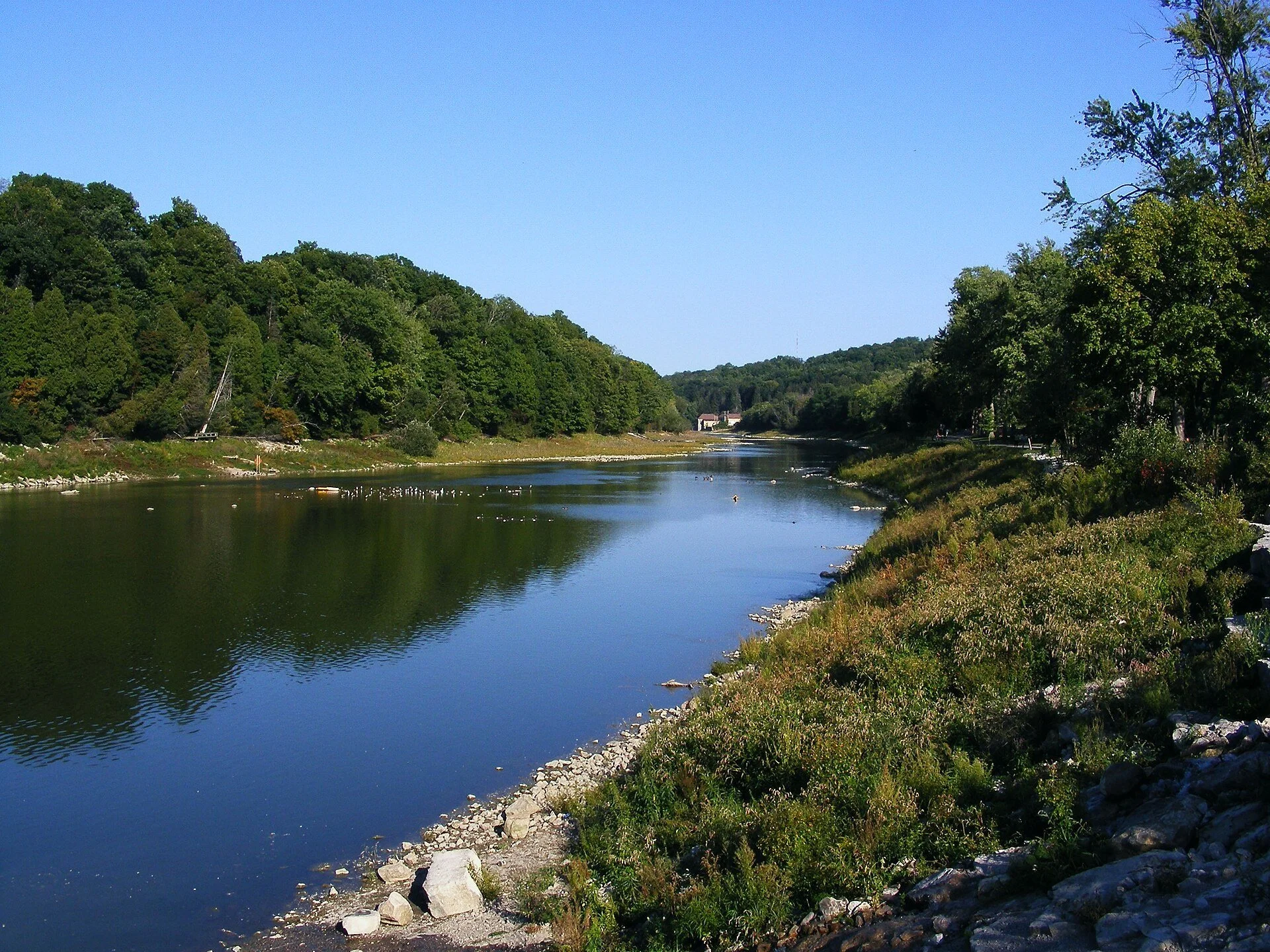 The Thames River curving between wooded banks at Springbank Park in London, Ontario.