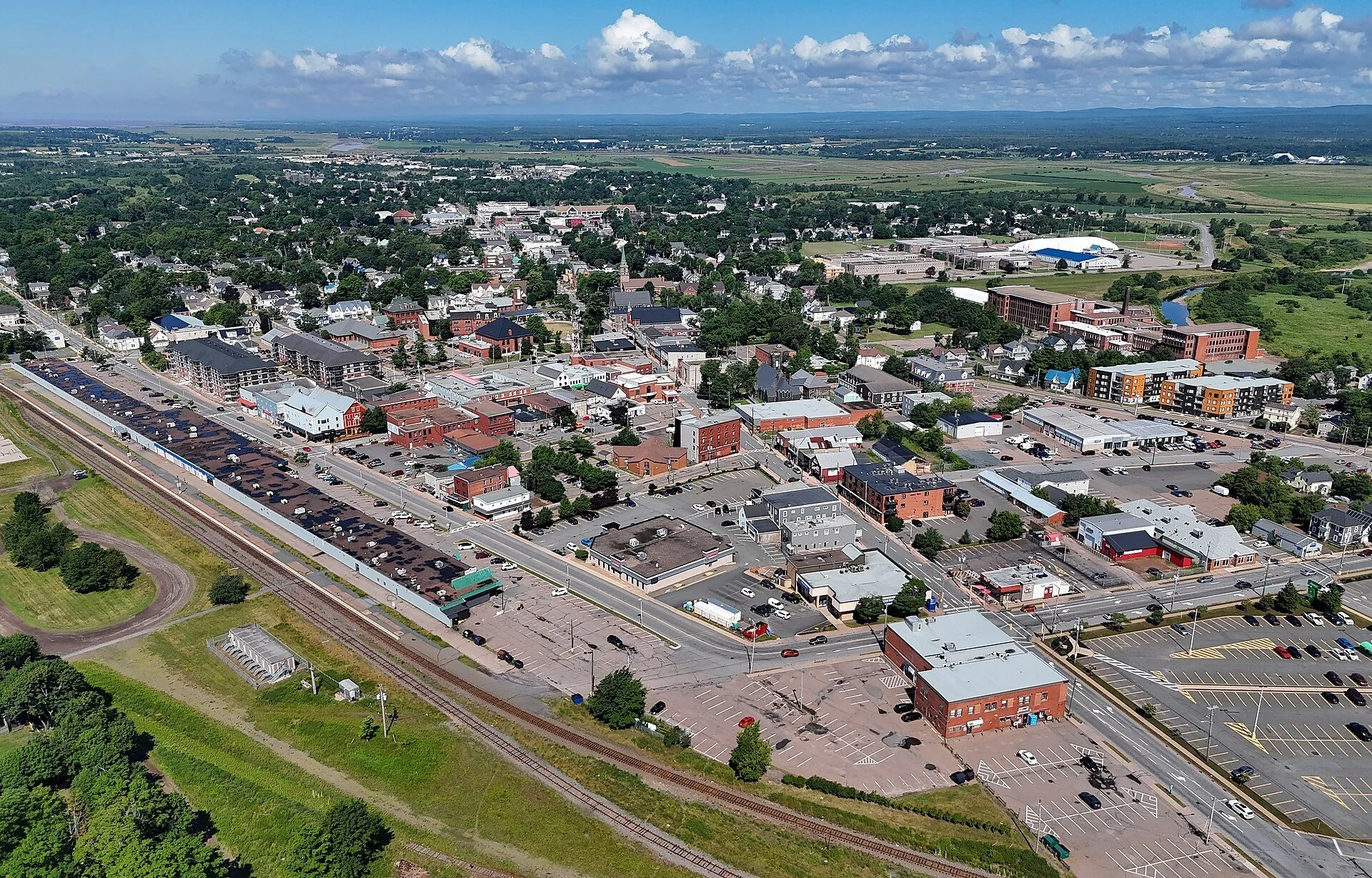 Aerial view of downtown Truro, Nova Scotia, with rail tracks and rooftops under a blue sky.