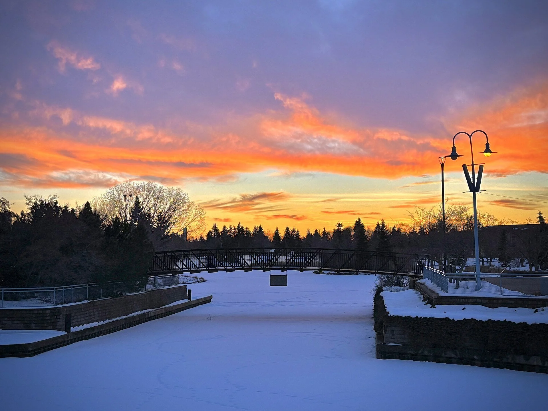 A colourful sunset over a snowy plaza and lamp posts in Sherwood Park, Alberta.