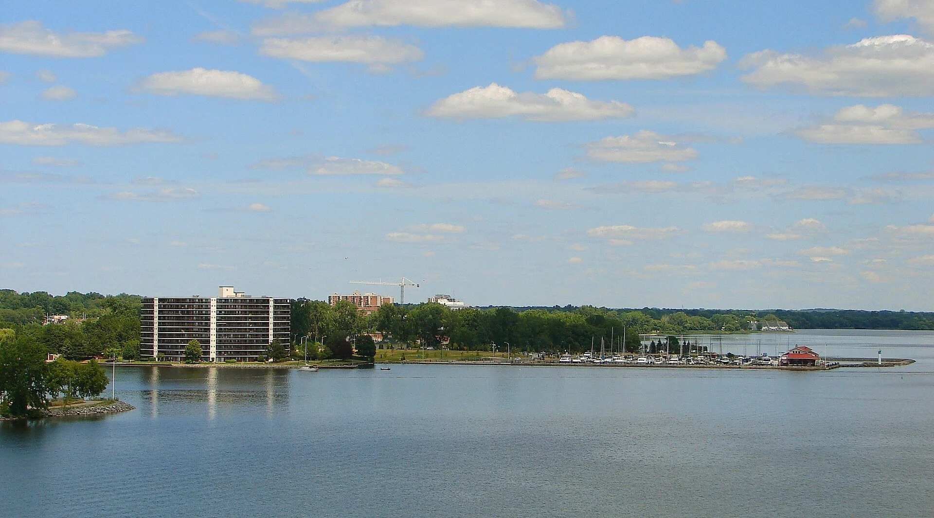 Calm water of the Bay of Quinte with the Belleville waterfront, a marina and apartment buildings on the far shore.
