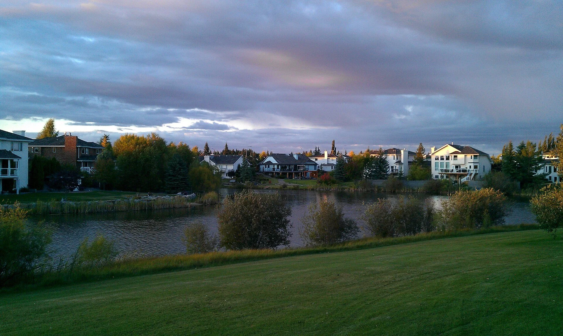 Homes beside a pond under a cloudy sky in Sherwood Park, Alberta.