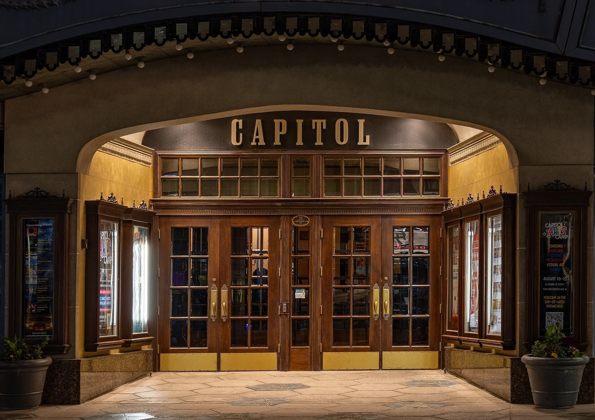 The lit wooden doors and marquee arch of the Capitol Theatre entrance in downtown Windsor at night.