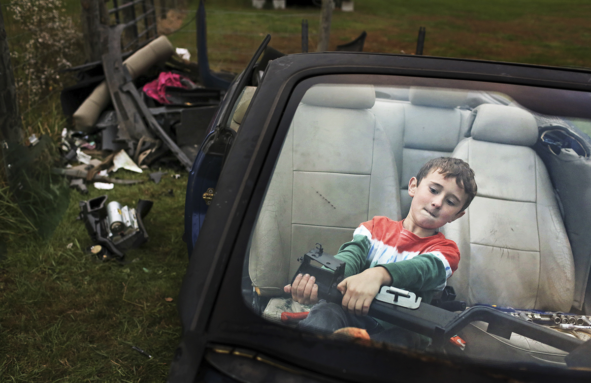 Blake Hendrix, 8, attempts to remove a part of the dash from an old Saab in the front yard of his home outside of Berea, K.Y.. Blake is helping to strip the car for parts to sell with his two brothers and two friends.