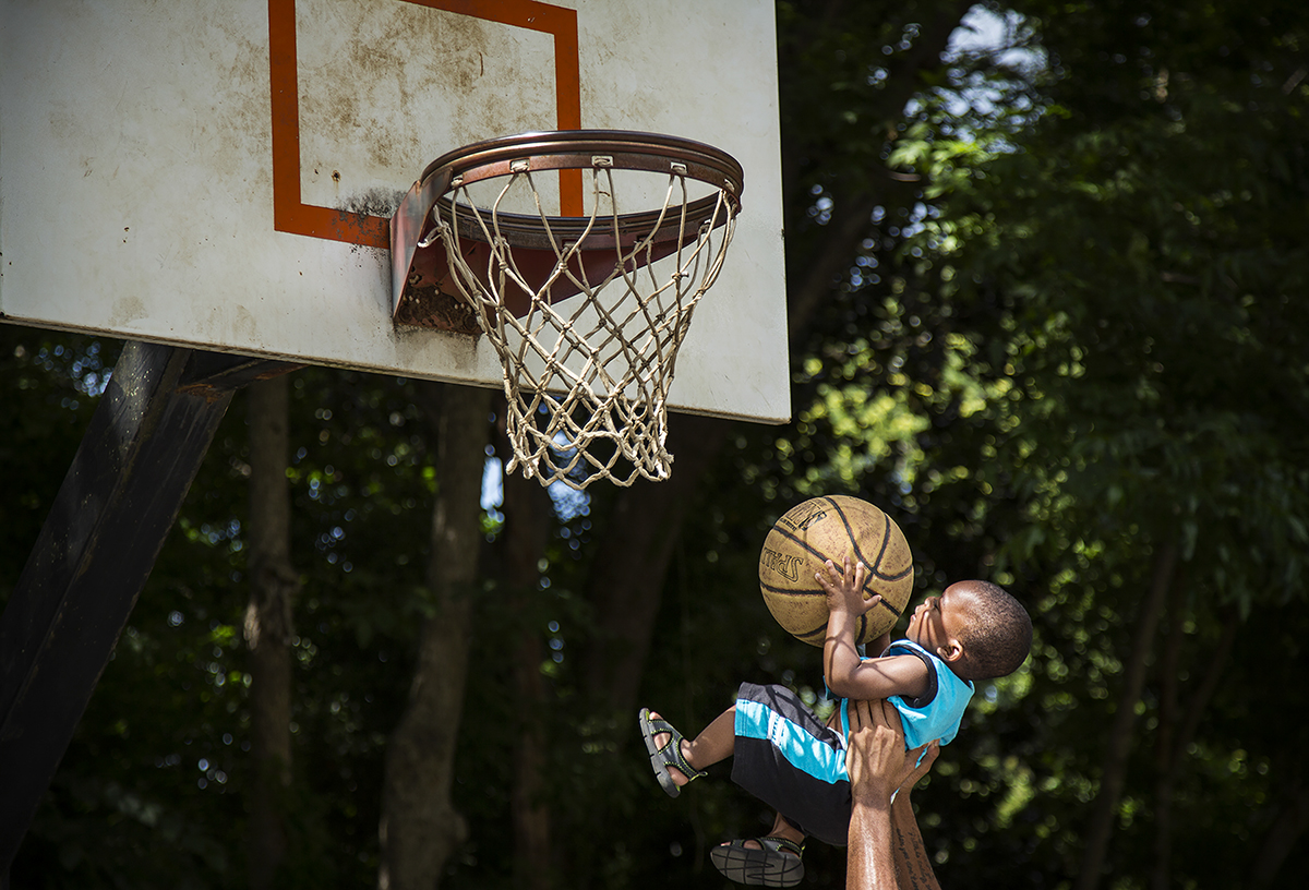  18 month-old Zyhier Gregory is lifted up by his uncle Derrick Conor to shoot a basket while playing basketball with his family in Freedom Park in Charlotte, N.C. on Saturday, June 13, 2015. Zyhier's father Darius Gregory says that Zyhier is learning