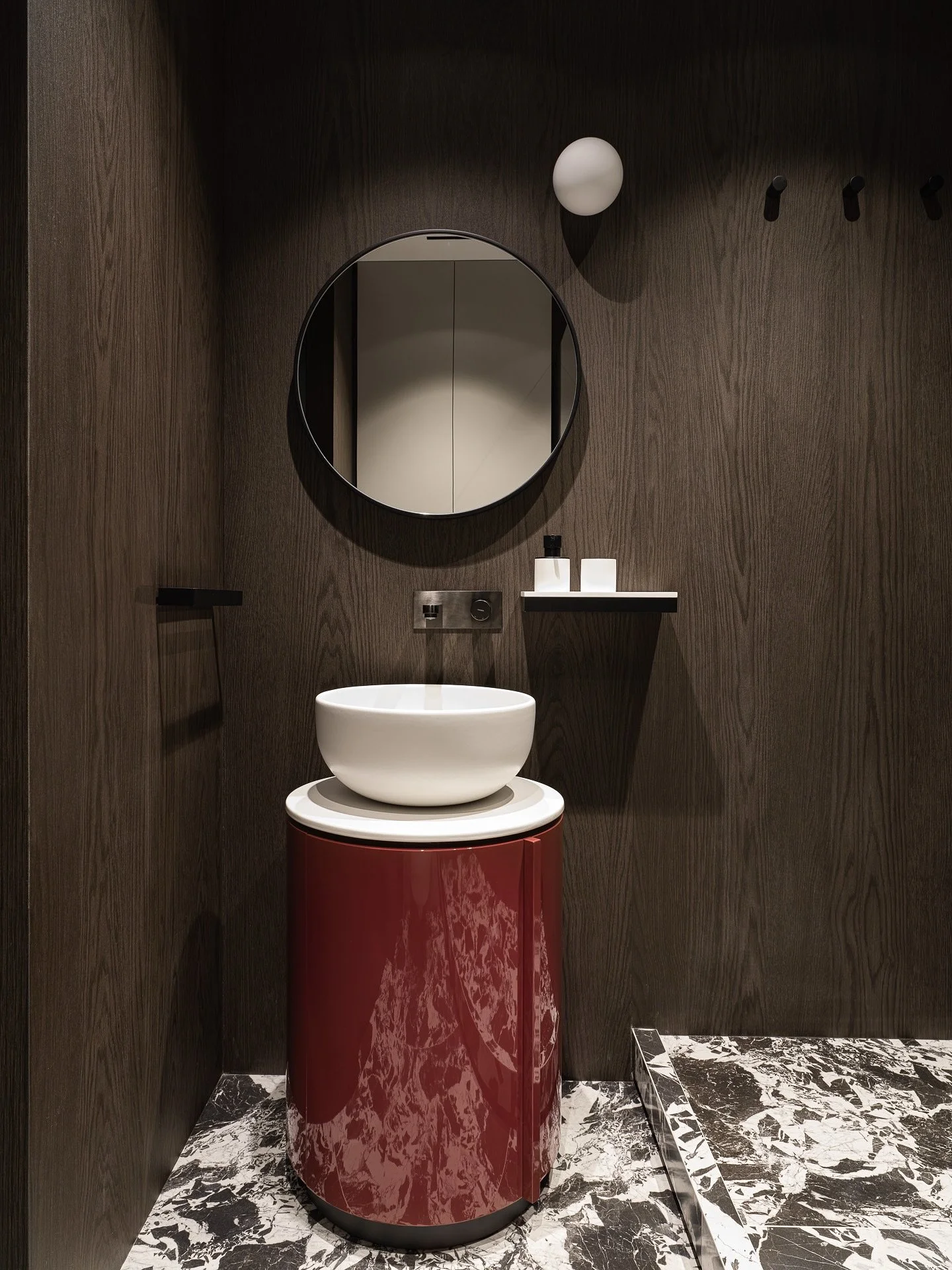 Основными акцентами санузла в проекте #MDNсобытие стали &laquo;шпонированные&raquo; стены и круглая глянцевая тумба в глубоком вишневом оттенке. 

Интерьер получился очень камерным и обволакивающим, темные стены как будто обнимают - очень любим испол