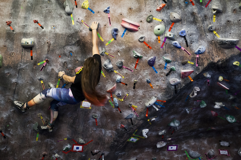 Woman bouldering at indoor climbing gym in Portland, Maine | Photo by Whitney J. Fox Photography