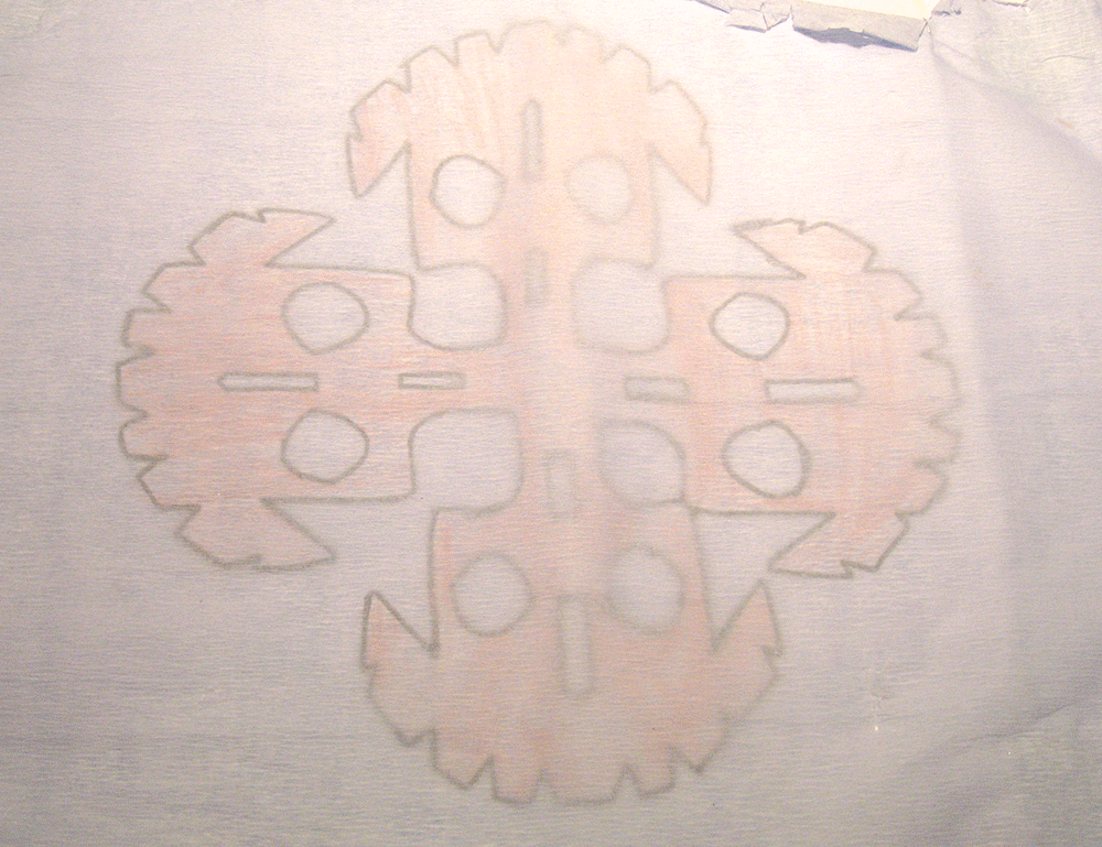 Esta mezcla de técnicas es muy interesante. La base es papel blanco. Tiene pegado un recorte de cruz con formas de calavera que fue coloreado con lápiz de color. Encima tiene una capa de papel crepé azul muy claro. Al ponerlo a contraluz se revelan las calaveras.
