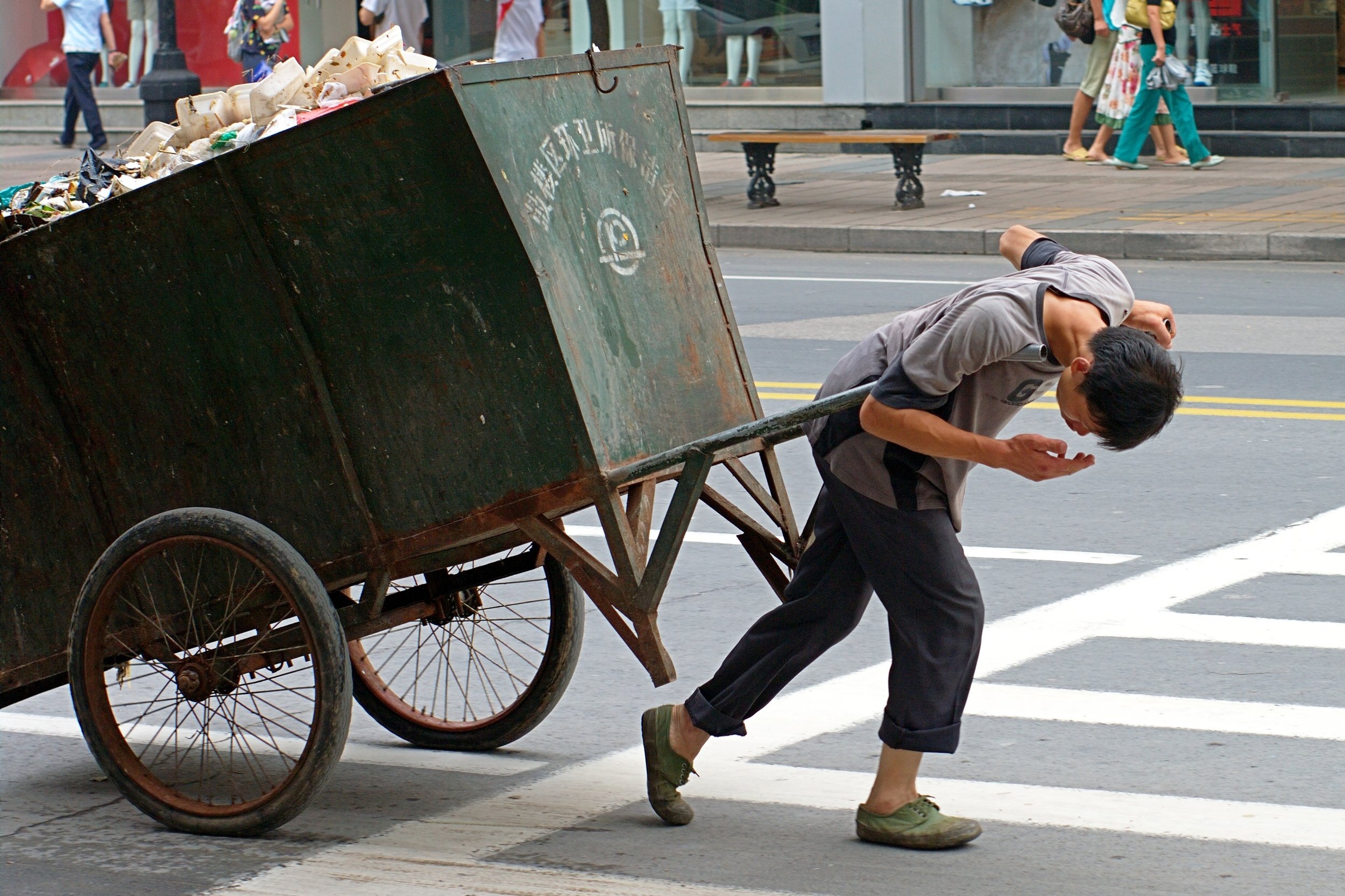A_man_is_suffering_pulling_a_trash.jpg