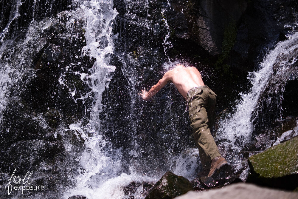  Jack dips his torso into the base of the waterfall. 
