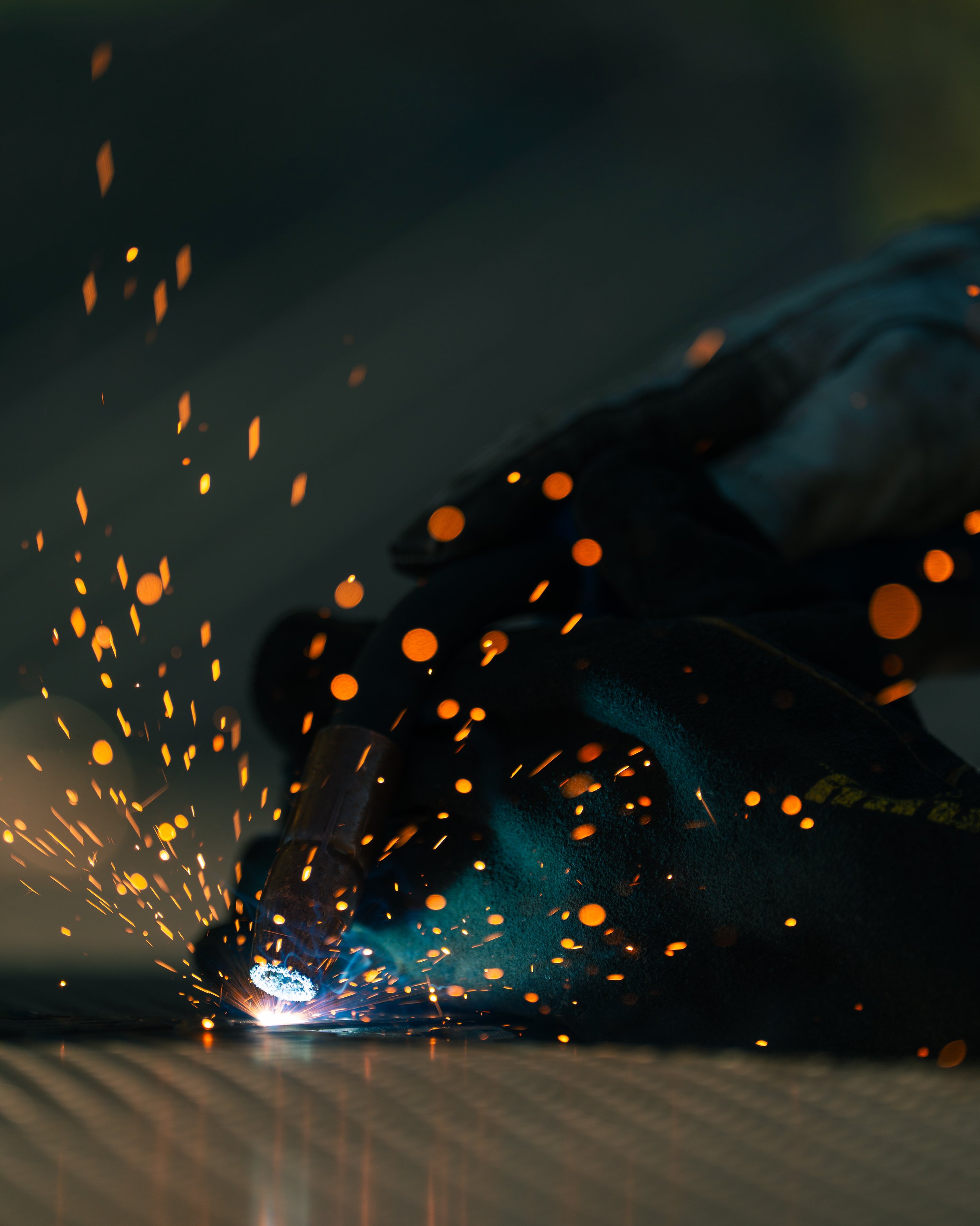 A close-up view of a person welding with a welding torch, sparks flying in all directions.
