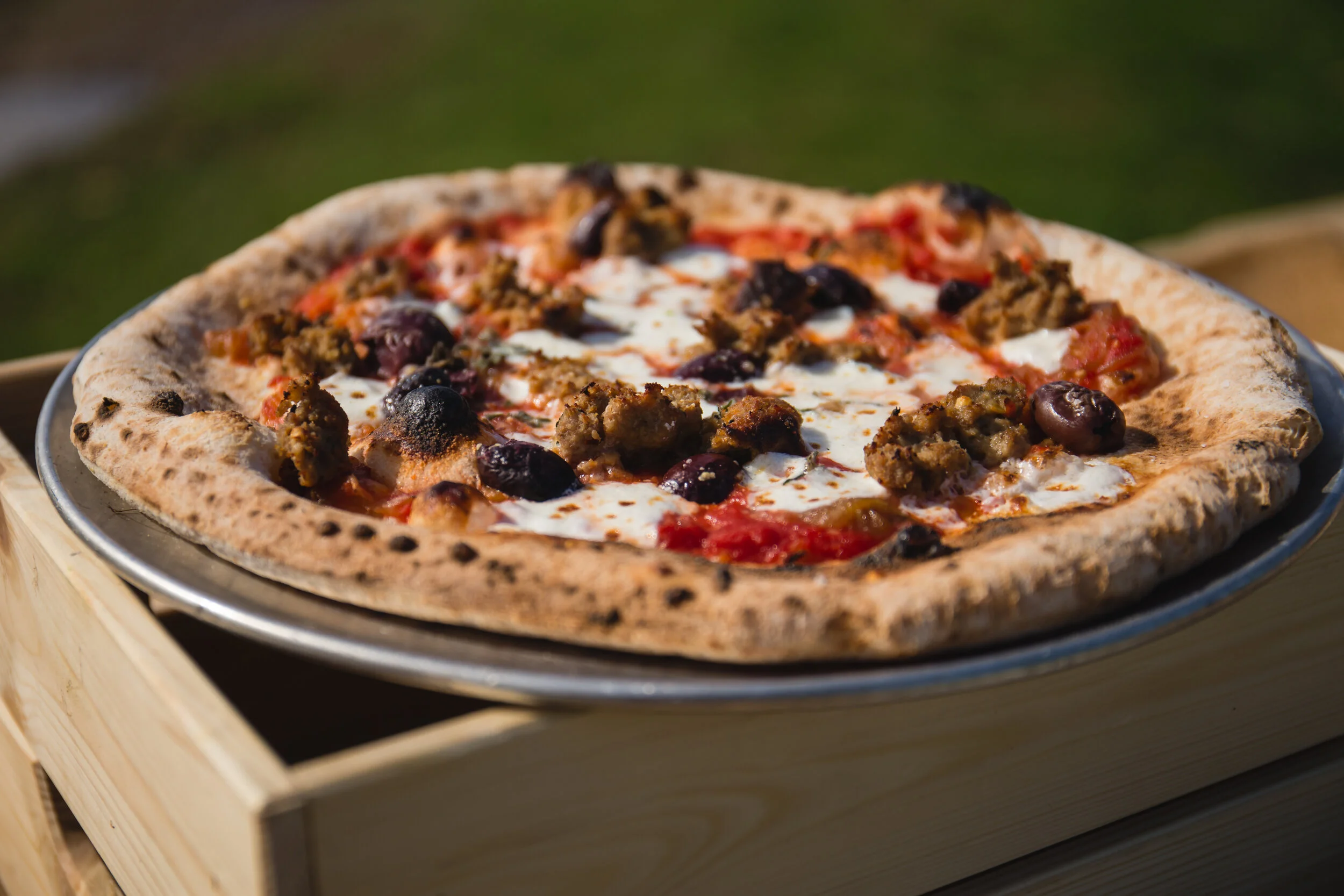 Wood fired sausage and olive pizza by Pizza Barbone catering on Cape Cod