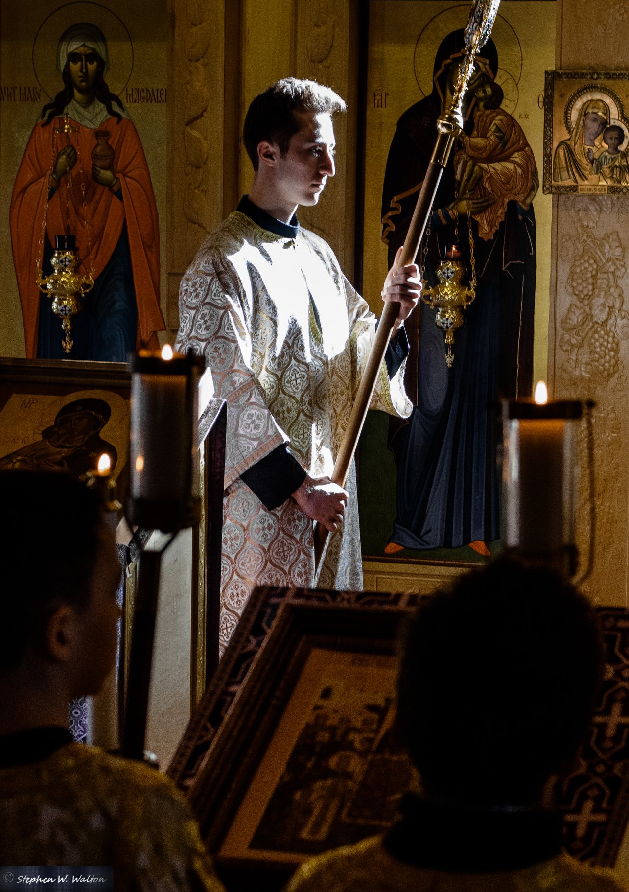  altar server holding processional fan in low light 