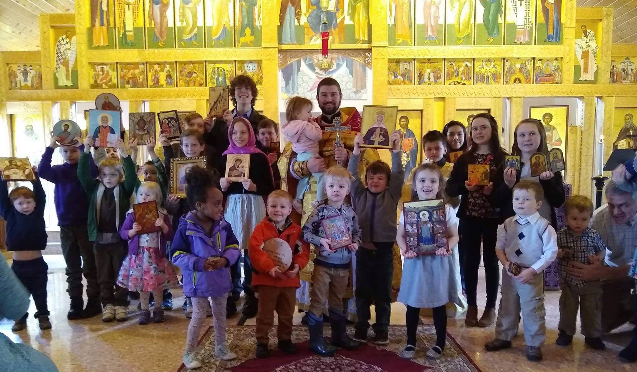  group picture of children holding icons with priest 