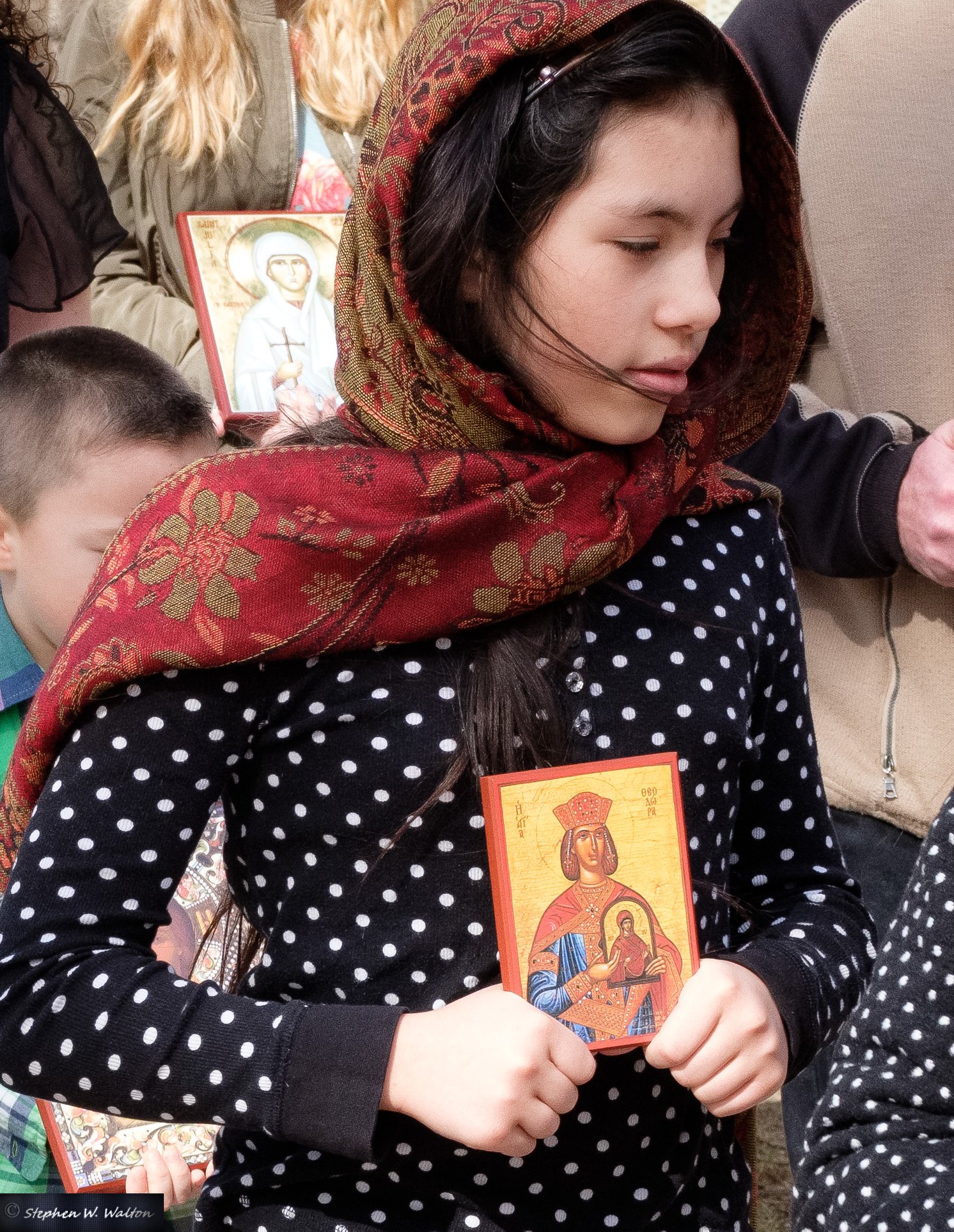 young girl with headscarf holding icon