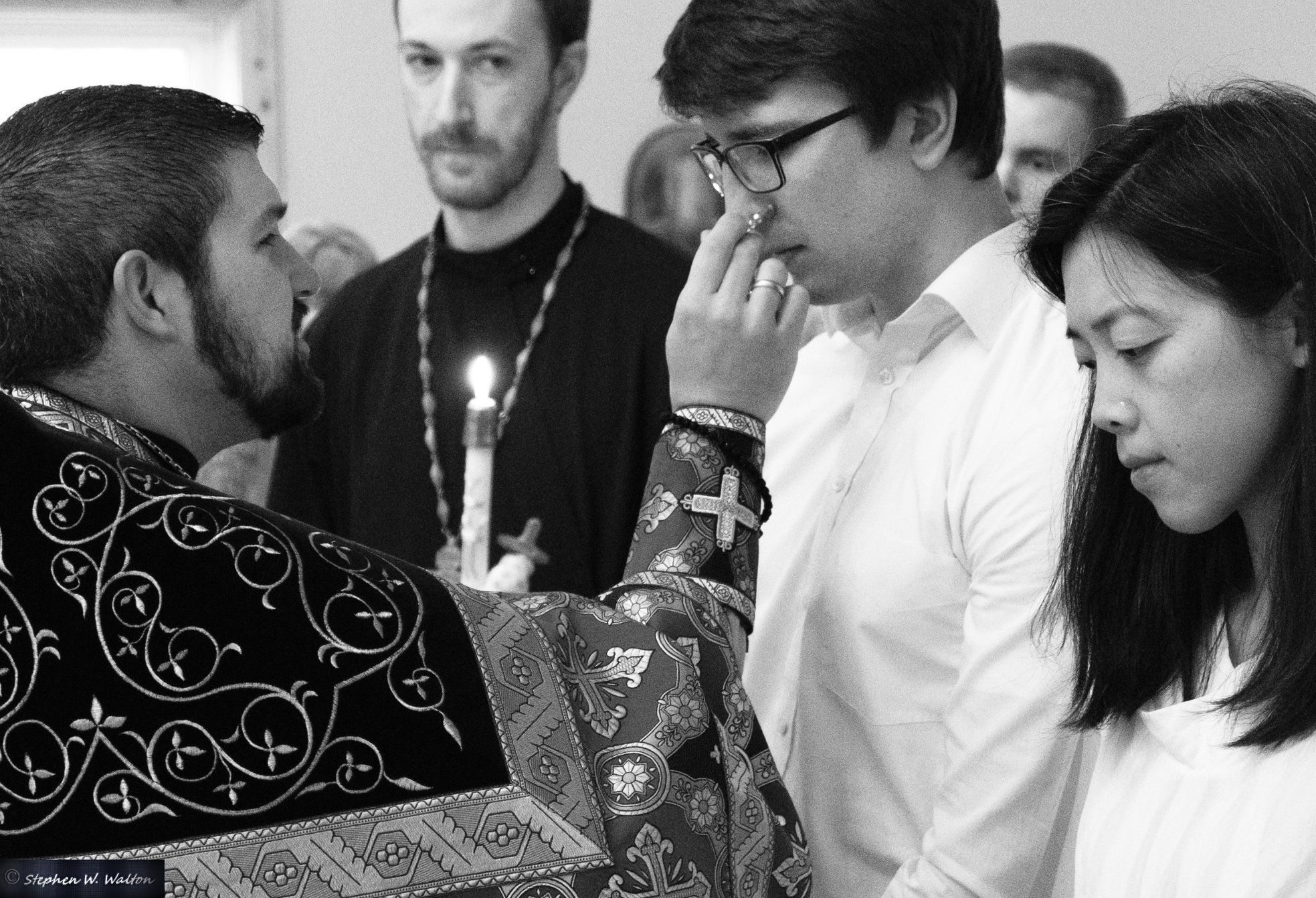 priest anointing young male with chrismation