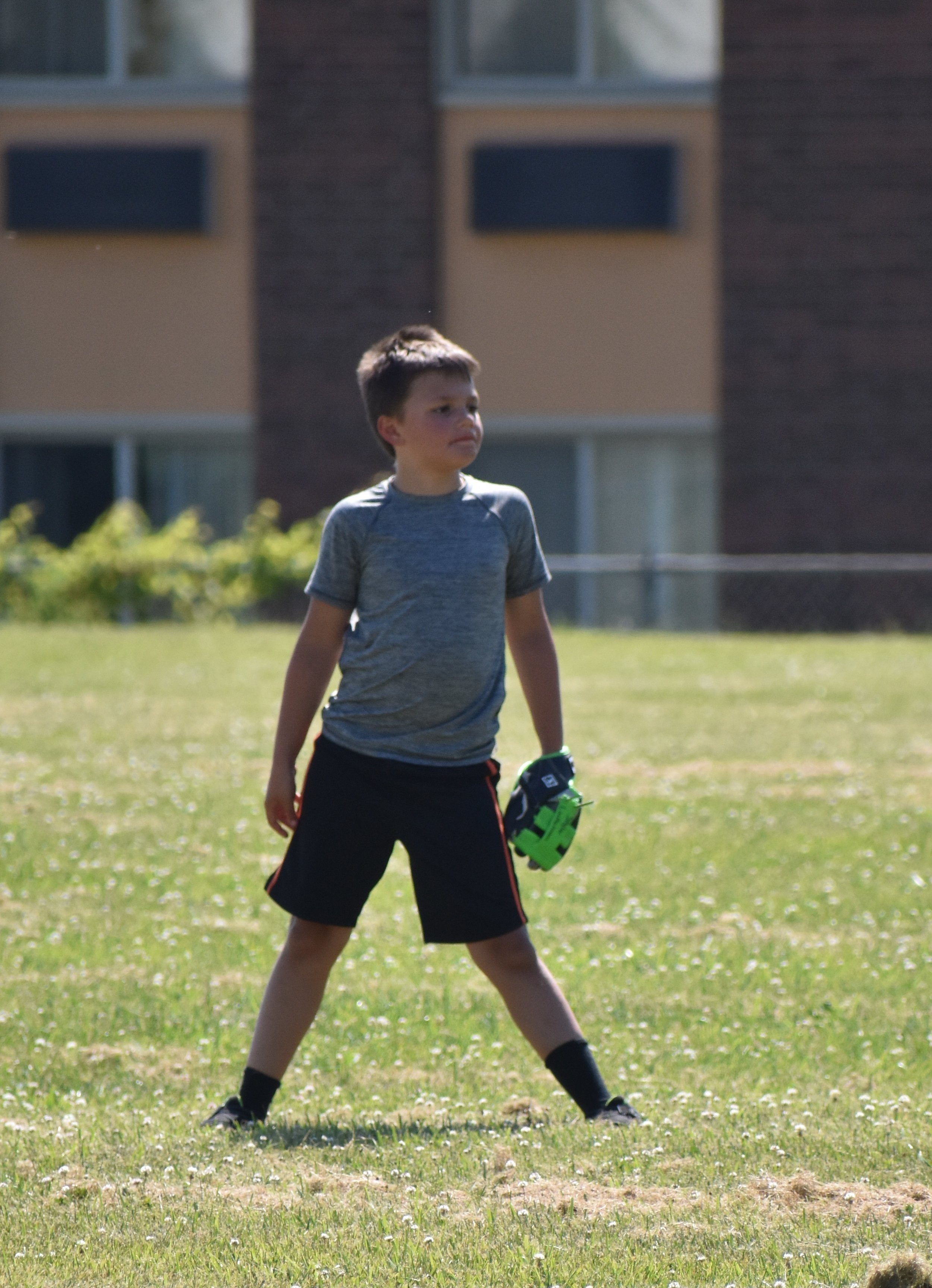  young boy standing in outfield 