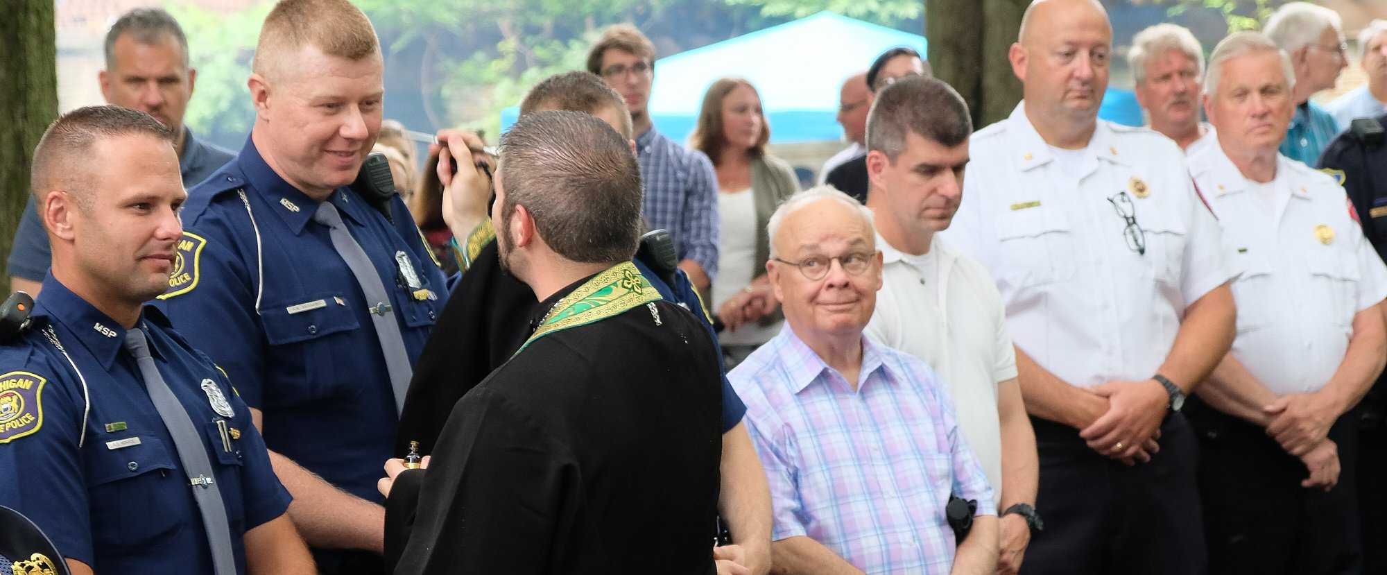 Fr. Gabriel anointing taller state trooper with Holy Chrism oil.