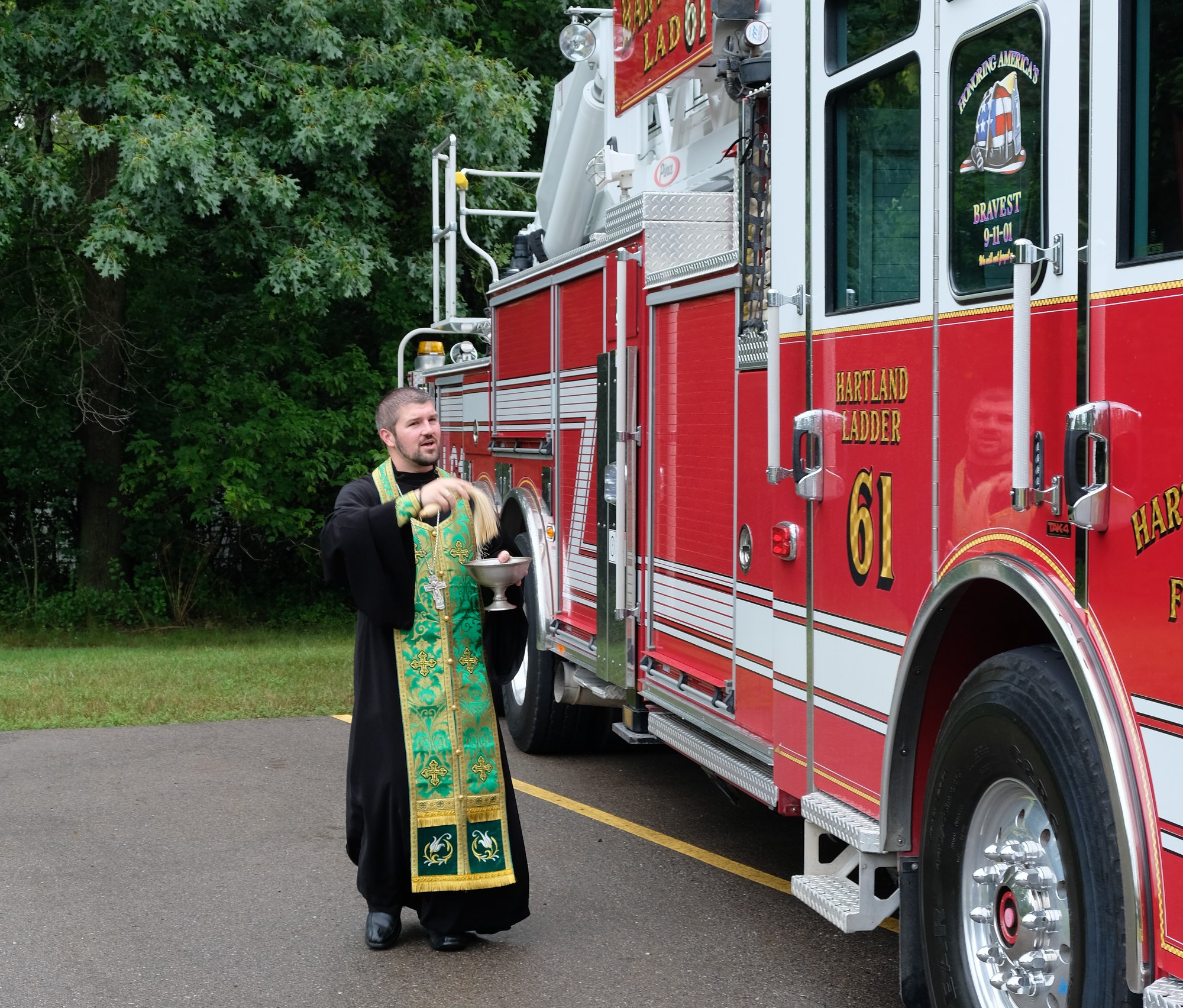  priest blessing fire truck with holy water 