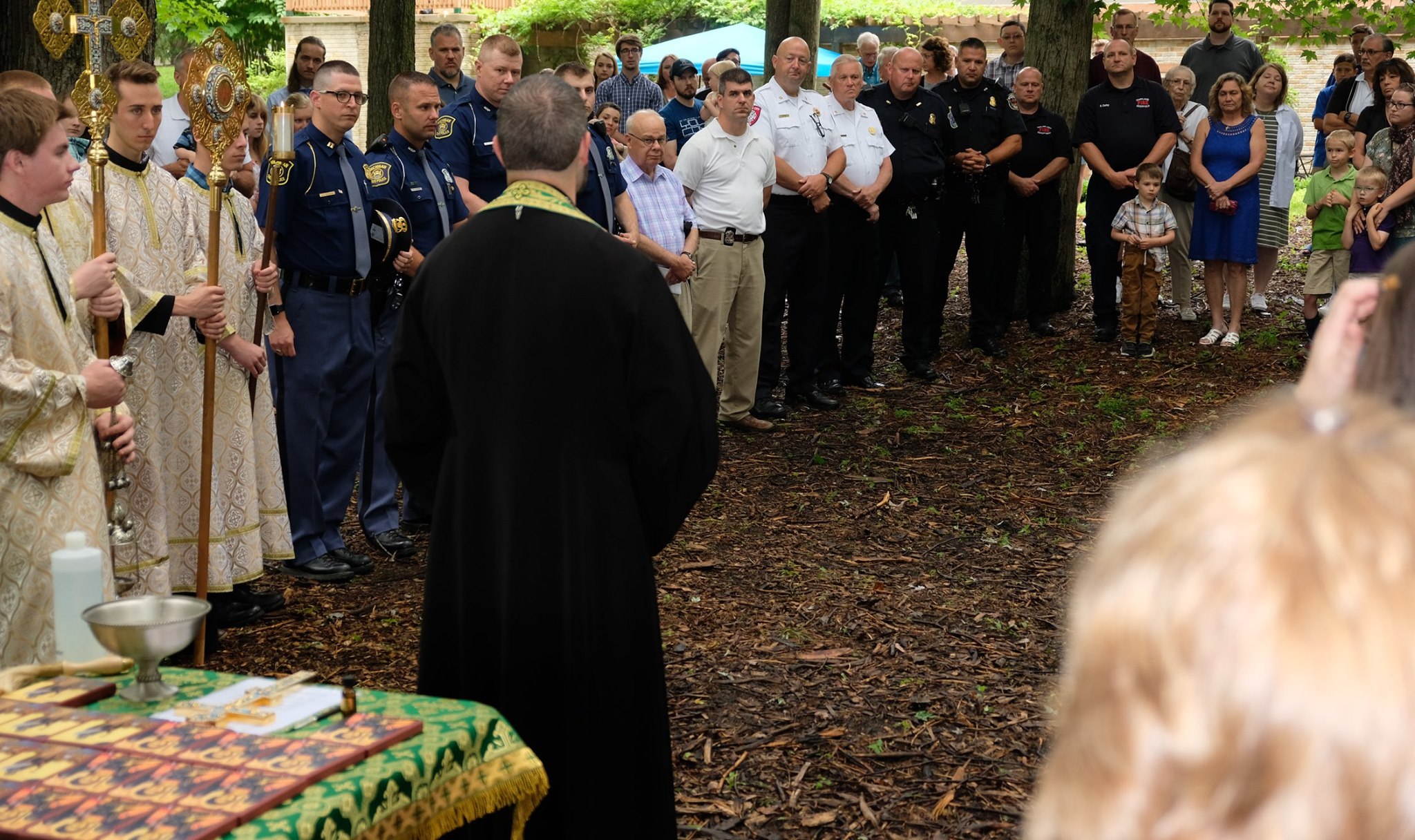  priest facing crowd of parishioners and first responders 