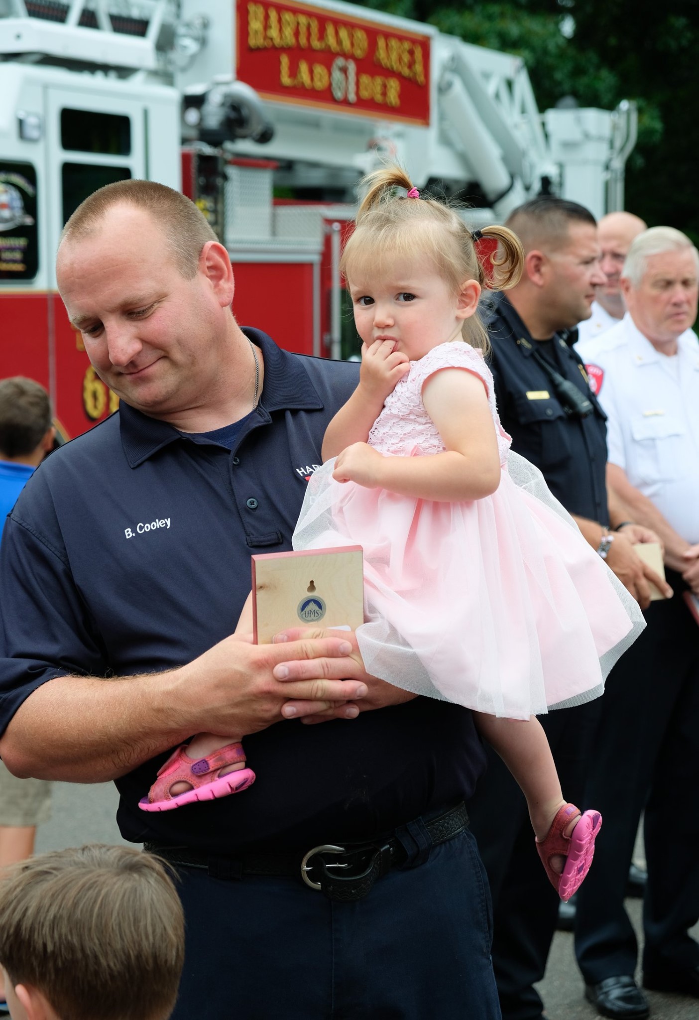 first responder father holding toddler daughter in pink dress