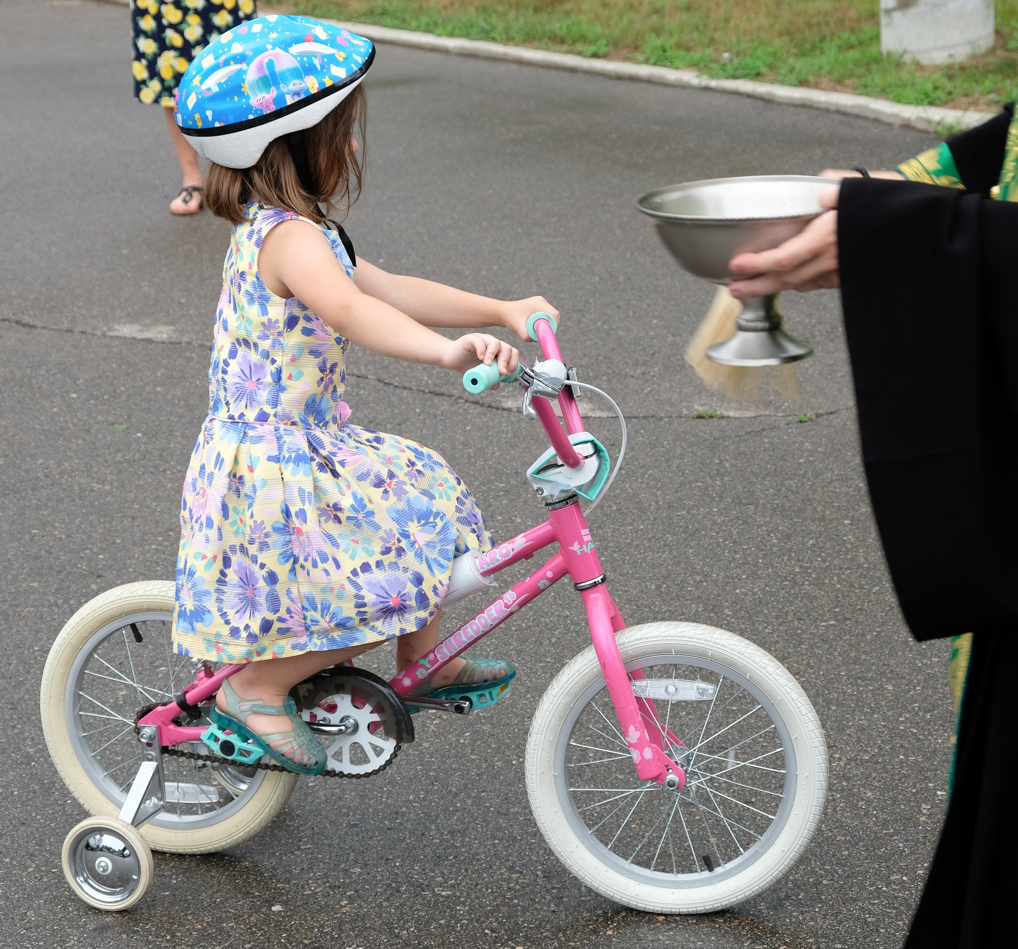  priest blessing young girl on a pink bike  