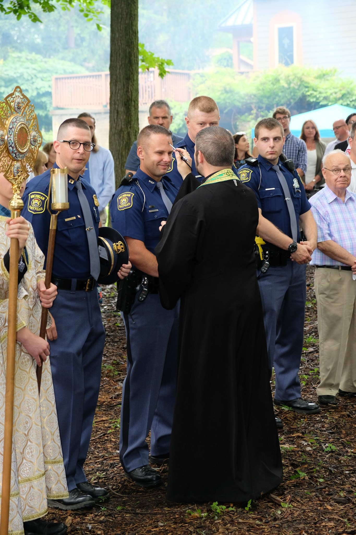 priest anointing state trooper with oil