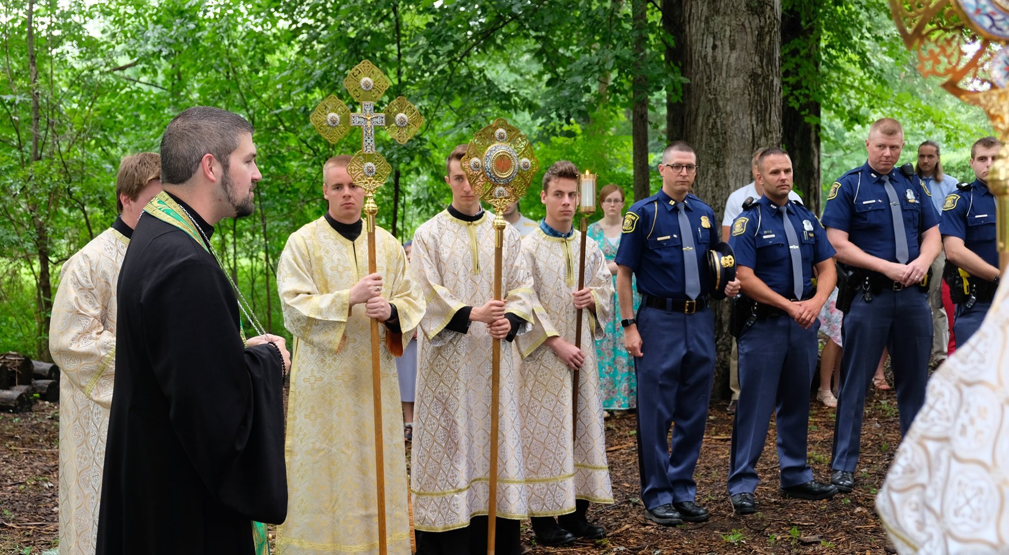  altar servers lined up next to state troopers with priest speaking  