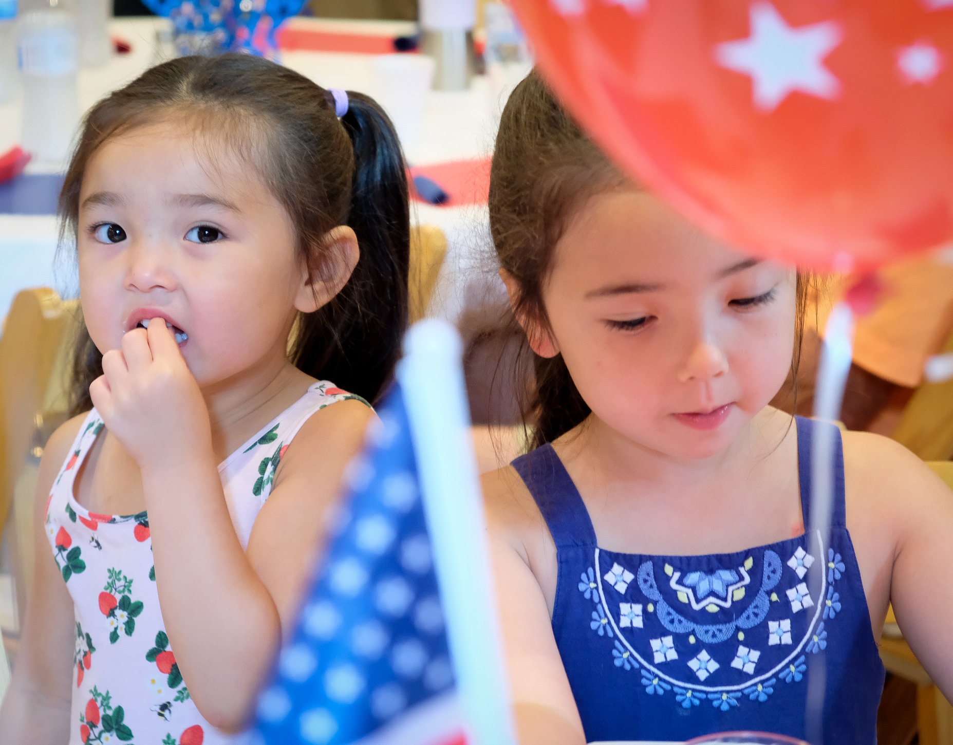 two sisters eating with balloon in forefront