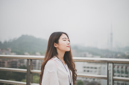 woman stands in public with eyes closed and is calm