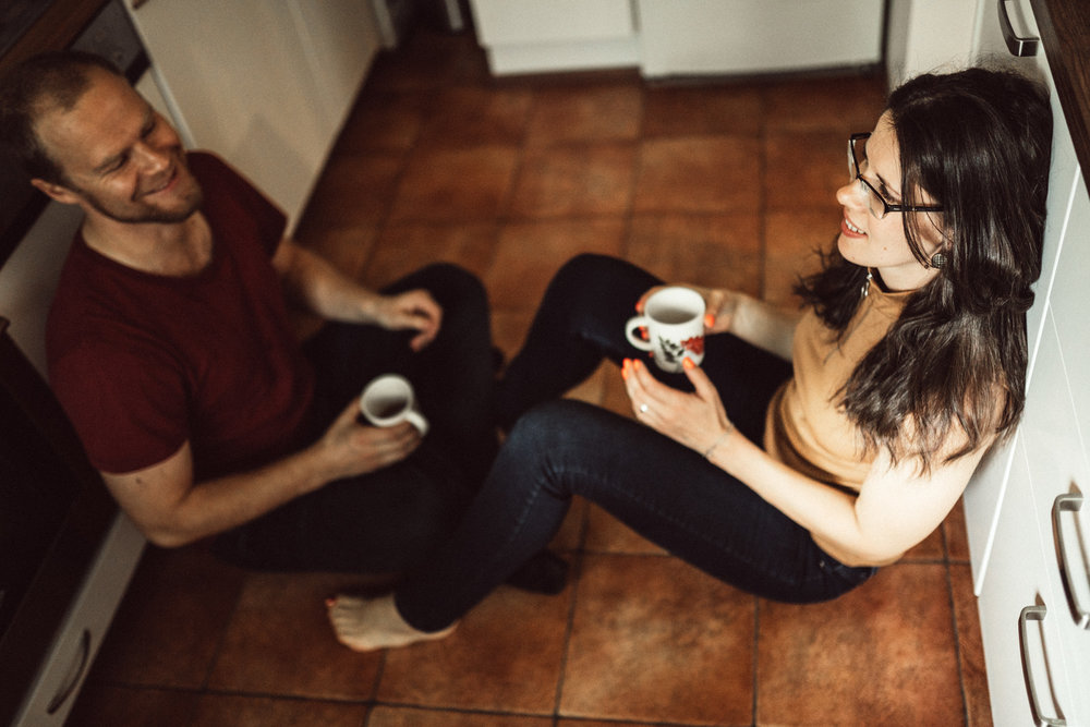 Beautiful couple sitting on kitchen floor at in-home photo session in Kuopio, Finland