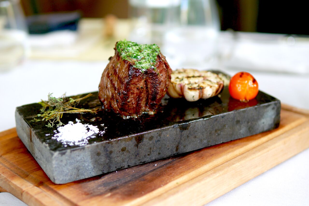 EESTI LIHAVEISE CHATEAUBRIAND 20€ Efektne ja kindla peale minek! Kel loomaliha isu on, siis see 200-grammine tükk rahuldab selle isu just täpselt nii palju, et magustoit mahub ka veel ja võib-olla isegi pisem eelroog ette. Lauda tuues levis meieni mõnus rosmariini aroom ja liha kärises ja särises täie hooga. Lihatükki oli imeline pooleks lõigata sest tekstuur oli suurepärane ja sisu oli veel punakas. Lõigatud lihatükid küpsesid kuumal laavakivil edasi veel seni kuni me nad sealt päästsime. Põhimõtteliselt oled sina roa laudatoomisest alates oma roa peakokk - küpseta palju tahad. Jällegi on mõeldud ka meie tervisele ja tulevale sügisle - ports küüslauku veel lisandiks kõrvale seatud.