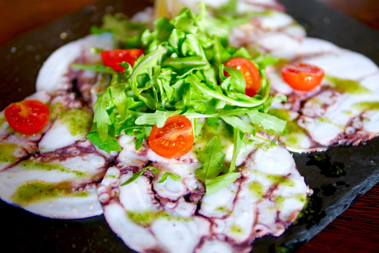 .... Kaheksajala-carpaccio 6,5€ Kaheksajala-carpaccio, ahjus kuivatatad kirsstomatid, marineeritud kukeseened Üks suurimaid üllatajaid õhtu jooksul! Kaheksjalga ei ole lihtne valmistada, sest see võib kiiresti omandada kummilaadse tekstuuri, rääkimata veel sellest, et see carpaccioks vorpida. See carpaccio osutus aga täielikuks HITT-roaks ja sai meil kiiresti otsa. Külmale kokkupressitud ja õhukesteks viiludeks lõigatud kaheksajalale oli kastmeks peale tilgutatud midagi pestolaadset, mis viis samuti keele alla. Menüü ütleb, et roog tuleb koos kukeseentega, kuid neid me taldrikult kahjuks ei leidnud. Kirsstomatid tundusid samuti pigem värsked, kui ahjus kuivatatud. Sellegipoolest oli roog väga hea ning tonaalsuse ja erksuse saavutamiseks võiks pigistada peale ka sidrunit. SOOVITAME VÄGA! .. Octopus carpaccio 6,5€ One of the biggest surprisers of the night! Octupus is a very tricky food when it comes to cooking, because it can easily get too rubbery if overcooked. Not to mention, making a carpaccio from it! But the carpaccio was a total HIT for us (and it disappeared off the plate very quickly as well). The sauce was somesort of pesto combined with olive oil or at least resembling it. The menu stated that the dish was with chanterelles, but we didn’t find them on our plate. Also, the cherry tomatoes were rather fresh than cooked in the oven. But it really does not make a big difference, because the dish was still good! For more of a balance and brightness we suggest you squeeze the lemon to top it all off. RECOMMEND! ....