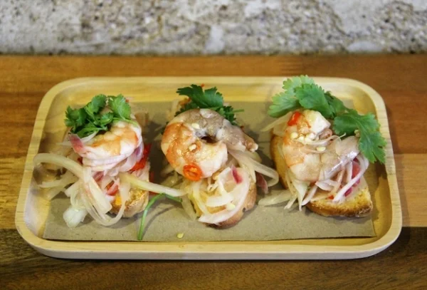 "Our Umai Bruschetta is a mash up of - Umai, a traditional native way of preparation of the Melanau people, and Bruschetta, a well known Italian started of toasted bread with toppings. The Umai prawn is ‘cooked’ lightly by calamansi lime juice, and mixed with onions & hillies served atop homemade Italian bread that has been lightly toasted. A simple, yet deliciously refreshing mash-up, perfect for the hot, Borneo climate. " 
