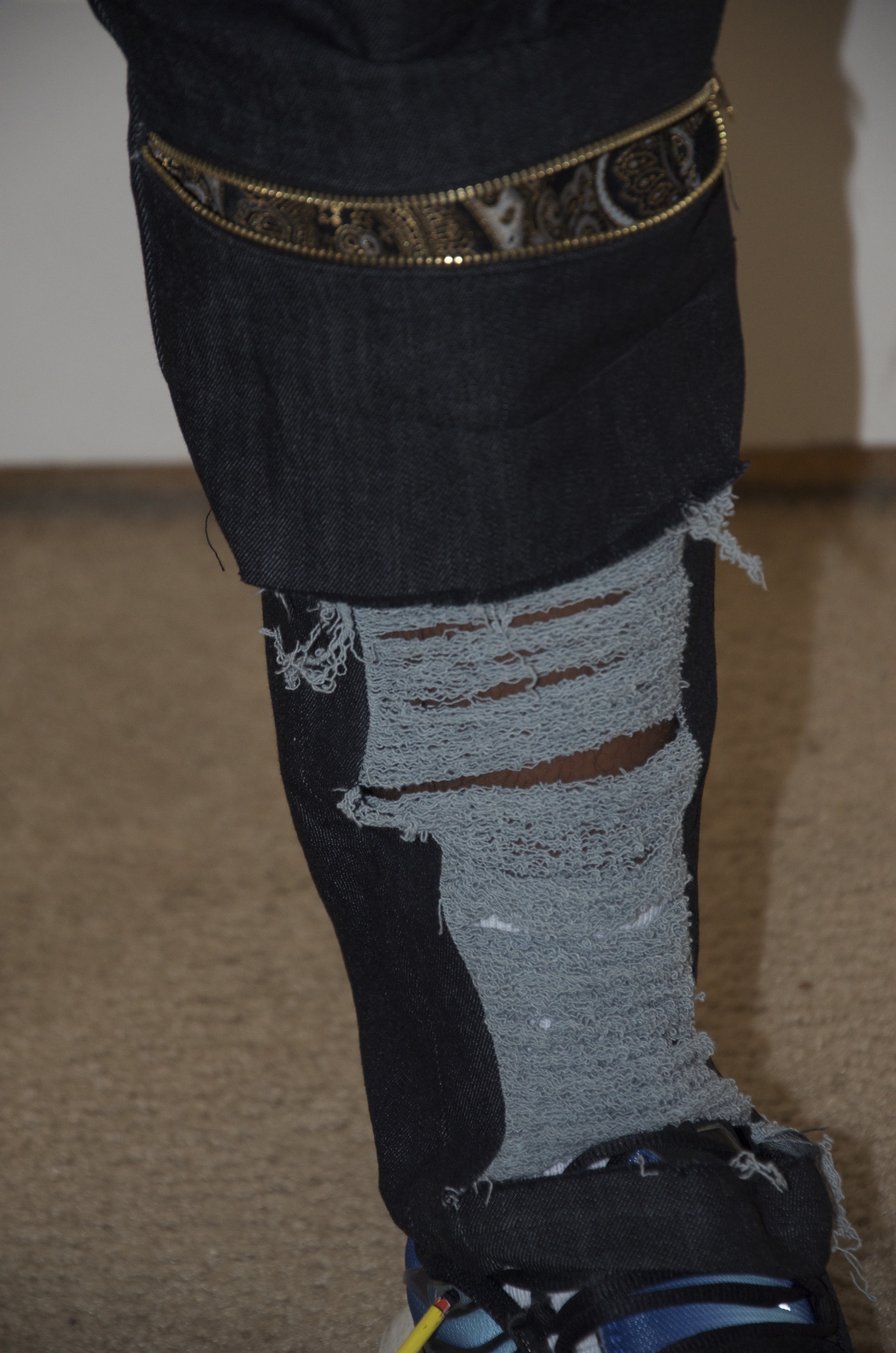 View of Left Knee with zipper instillation at the knee, with fabric attachment behind knee. Descending distress at calf muscle.