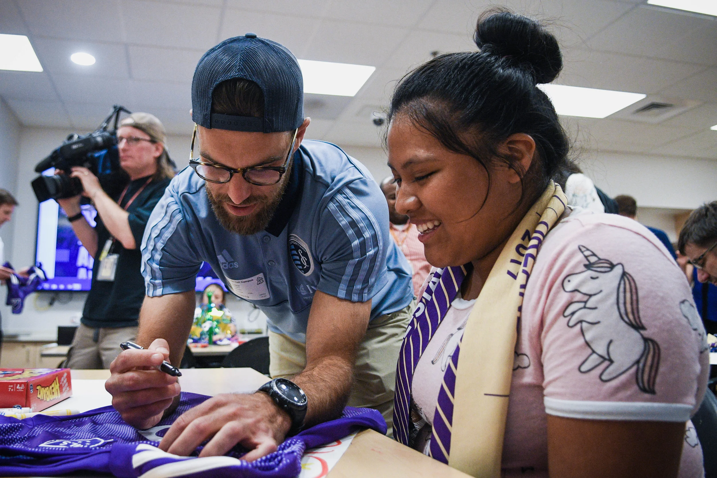 Sporting Kansas City defender Graham Zusi signs a jersey for a patient after he was surprised at Children’s Mercy Hospital in Kansas City with the news he was voted on to the 2019 Major League Soccer All-Star team. This will be Zusi’s 7th appearance on the all-star roster.