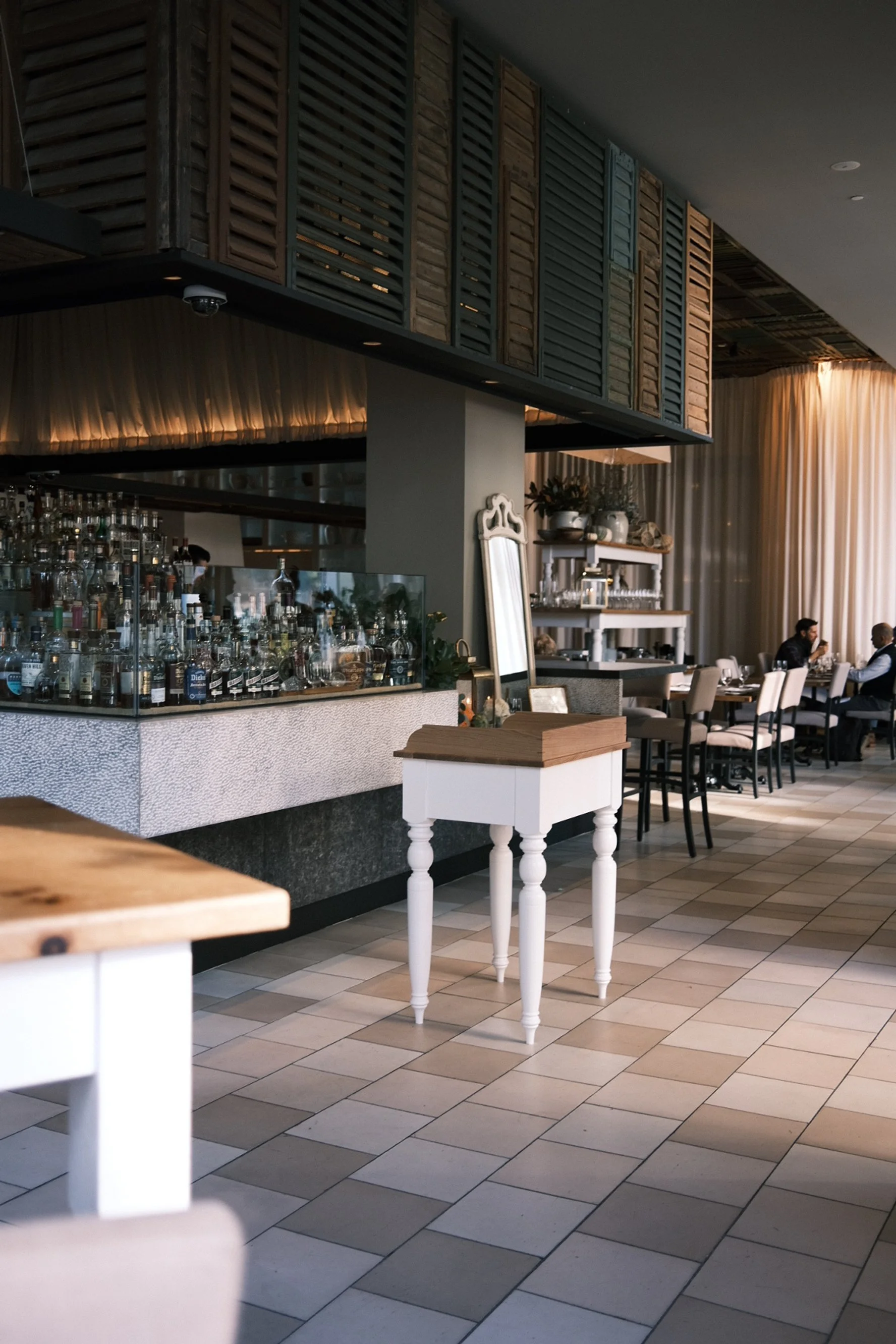 White oak host stand with painted turned legs in the dining room at Ella Dining Room & Bar, Sacramento