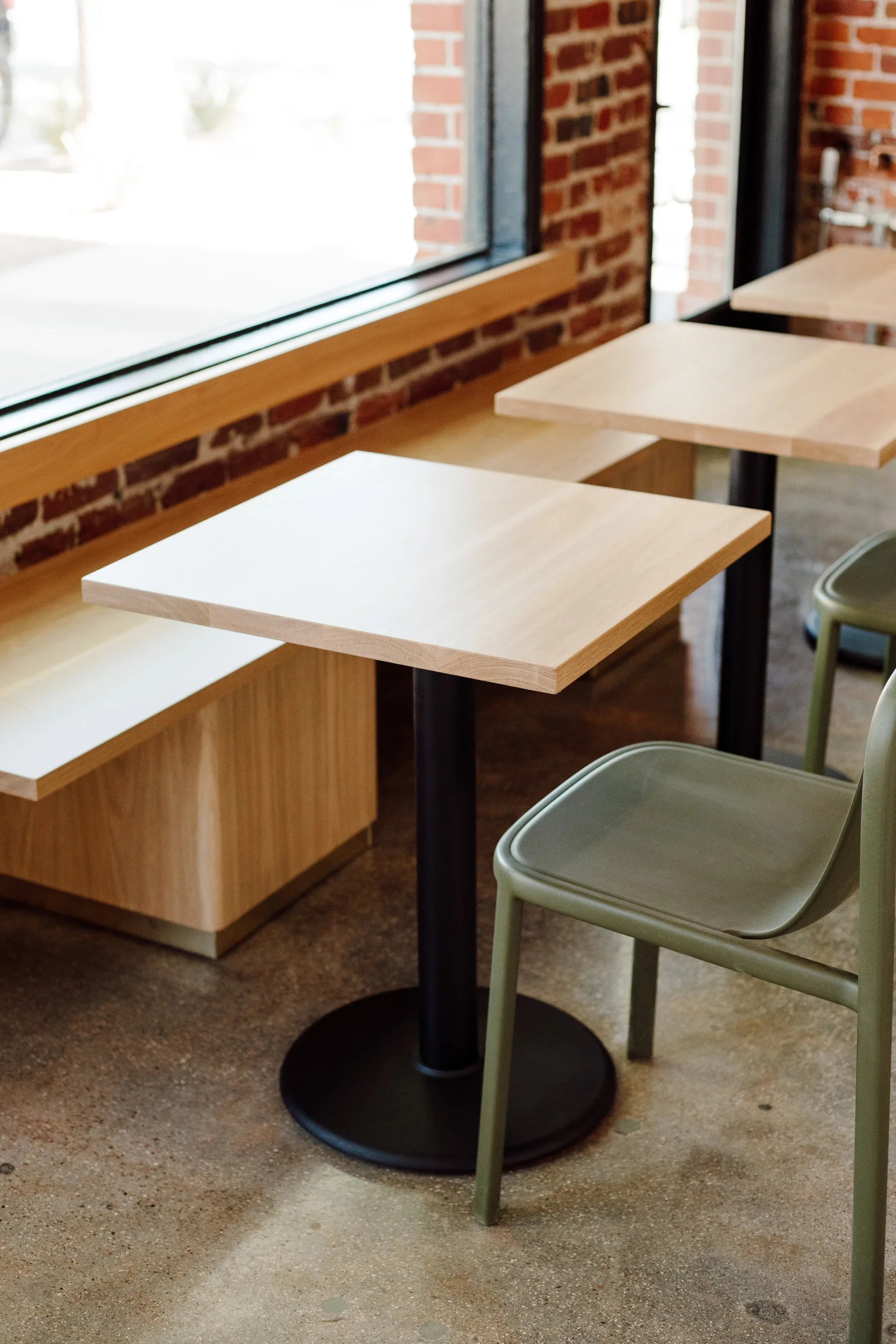 White oak window-bar ledge and café tables with sage green chairs at Mast Coffee on Broadway