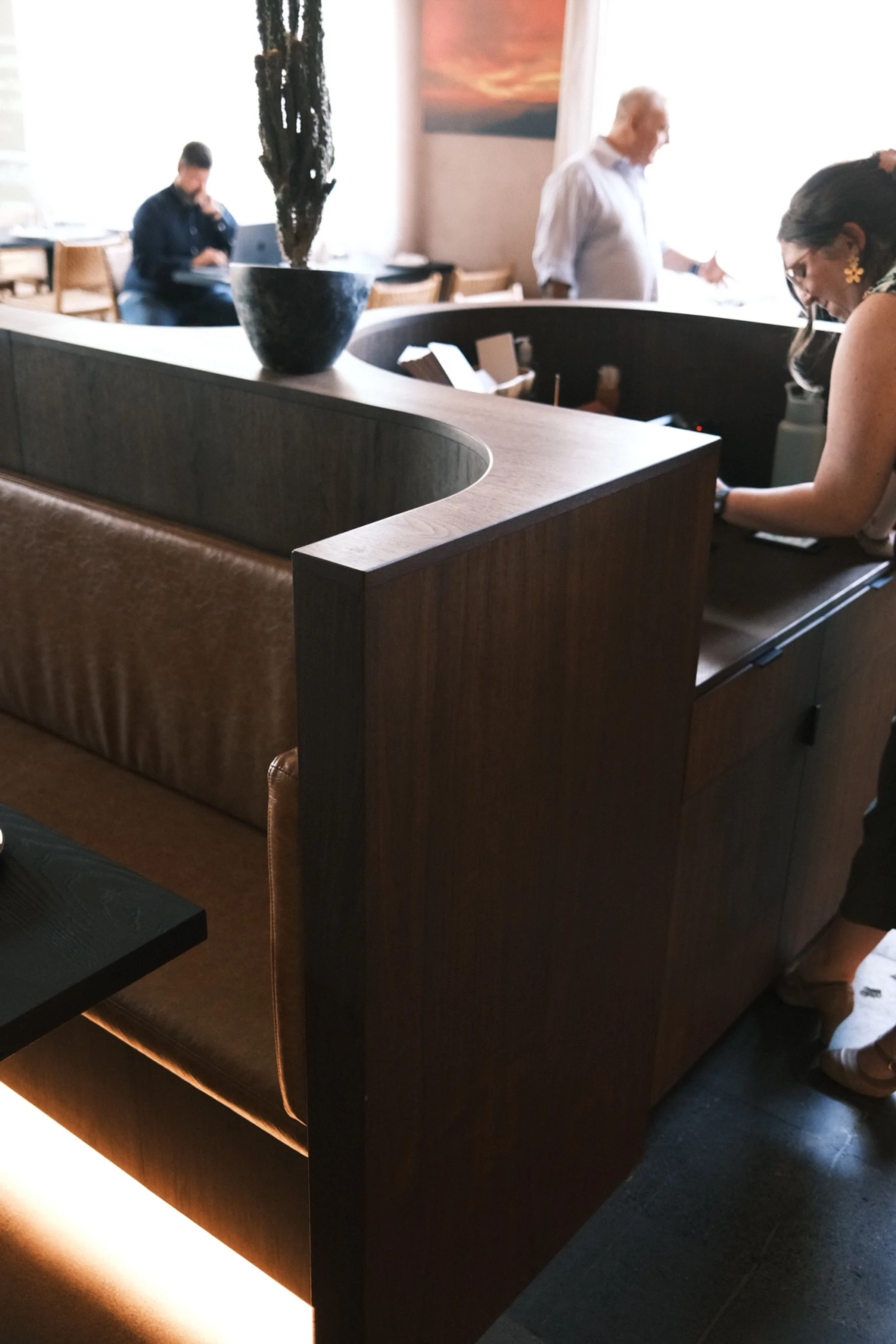 Curved banquette end in dark-stained veneer with leather seat at Cantina Pedrigal