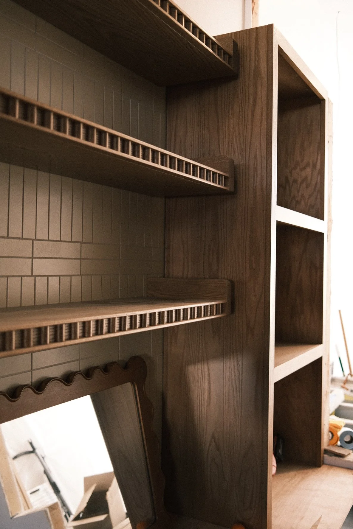 White oak floating shelves with slatted rail fronts against vertical tile at Little While, San Diego