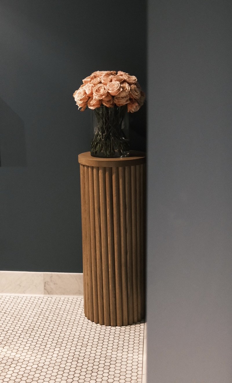 Fluted white oak pedestal plinth against a dark wall at The Kitchen restaurant